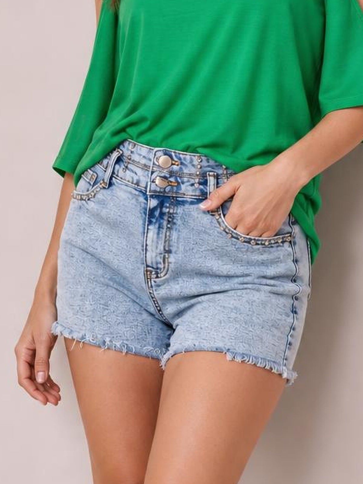 Model poses in light wash high-waist denim shorts with a fitted silhouette, button fly, rhinestone-trimmed pockets, and frayed raw hems.