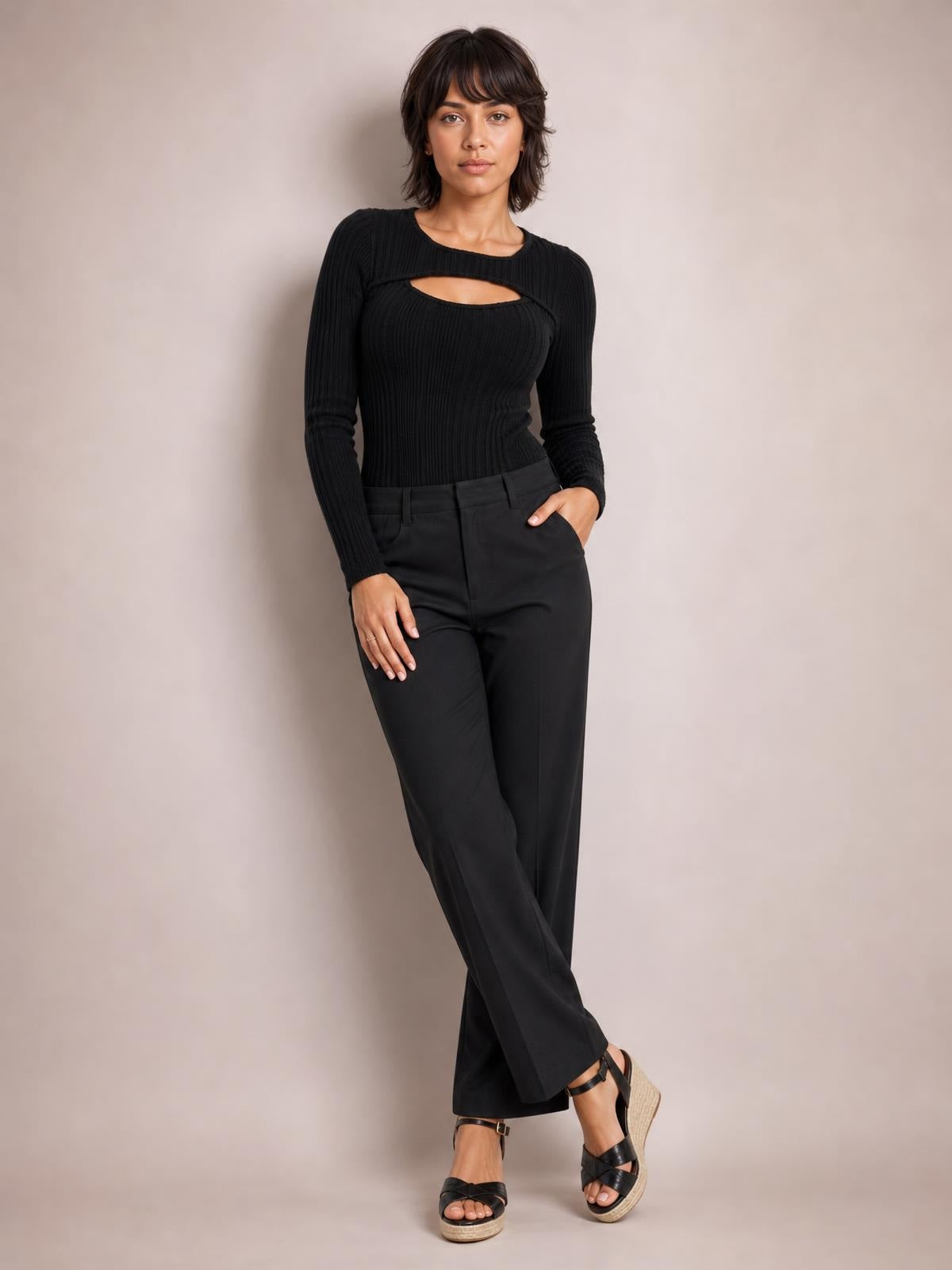 Model wears a black ribbed cutout round-neck bodysuit with long sleeves and a fitted silhouette, posing with one hand in her trouser pocket.