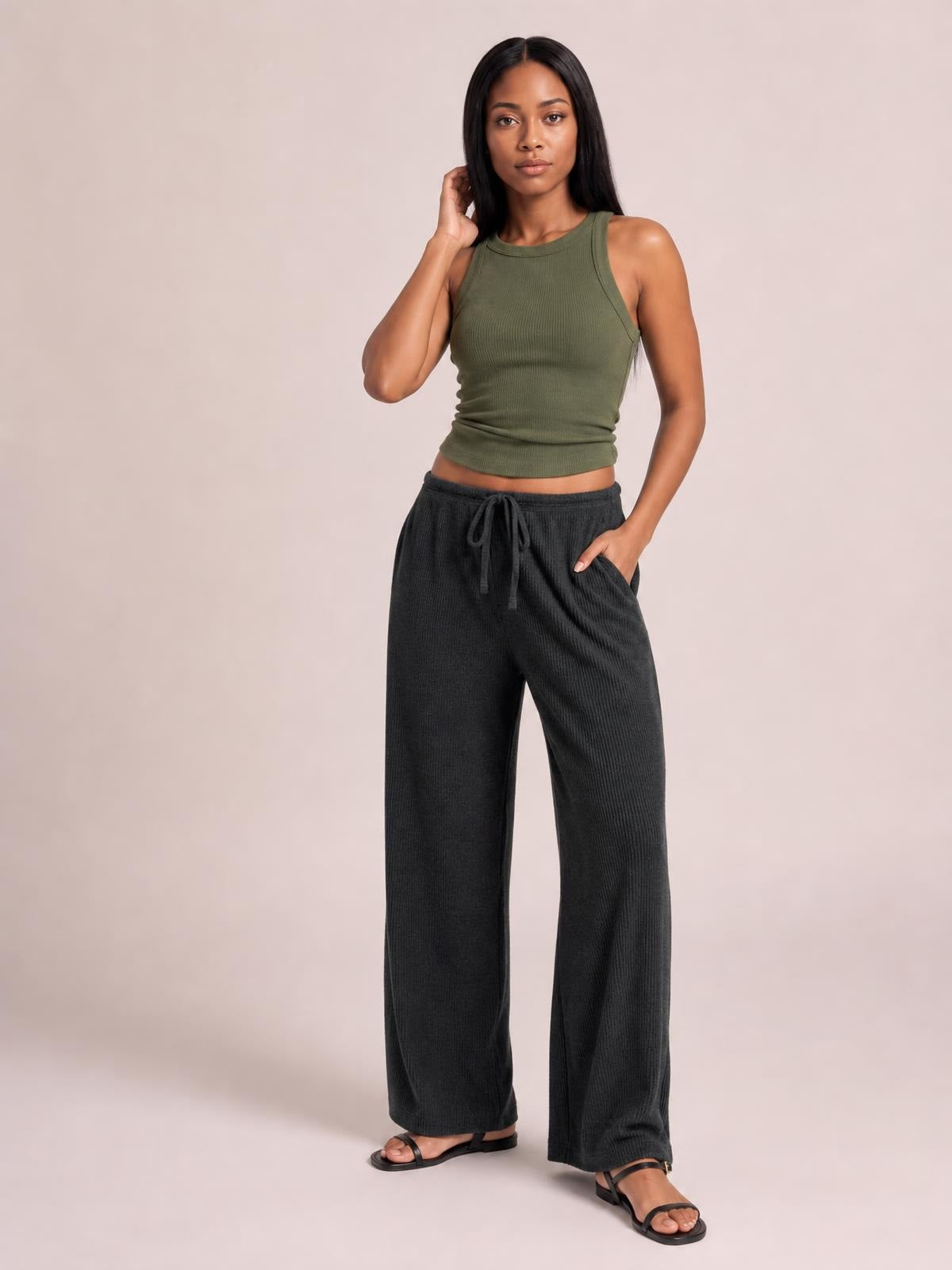 Model wears black ribbed drawstring wide-leg pants with a relaxed silhouette and side pockets, standing with one hand in a pocket.