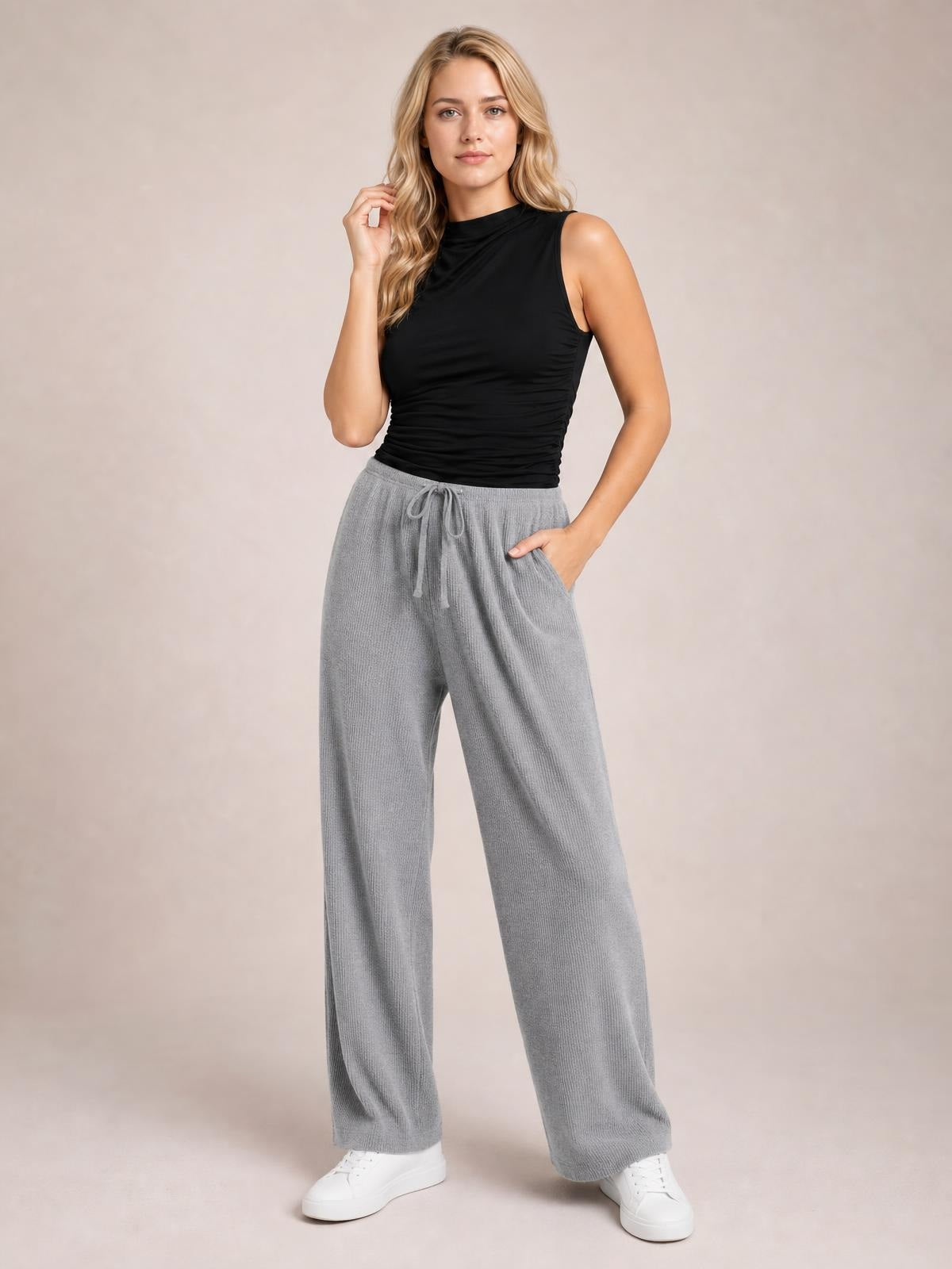 Model poses in gray ribbed drawstring wide-leg pants with side pockets, an easy relaxed silhouette, and a black sleeveless top.