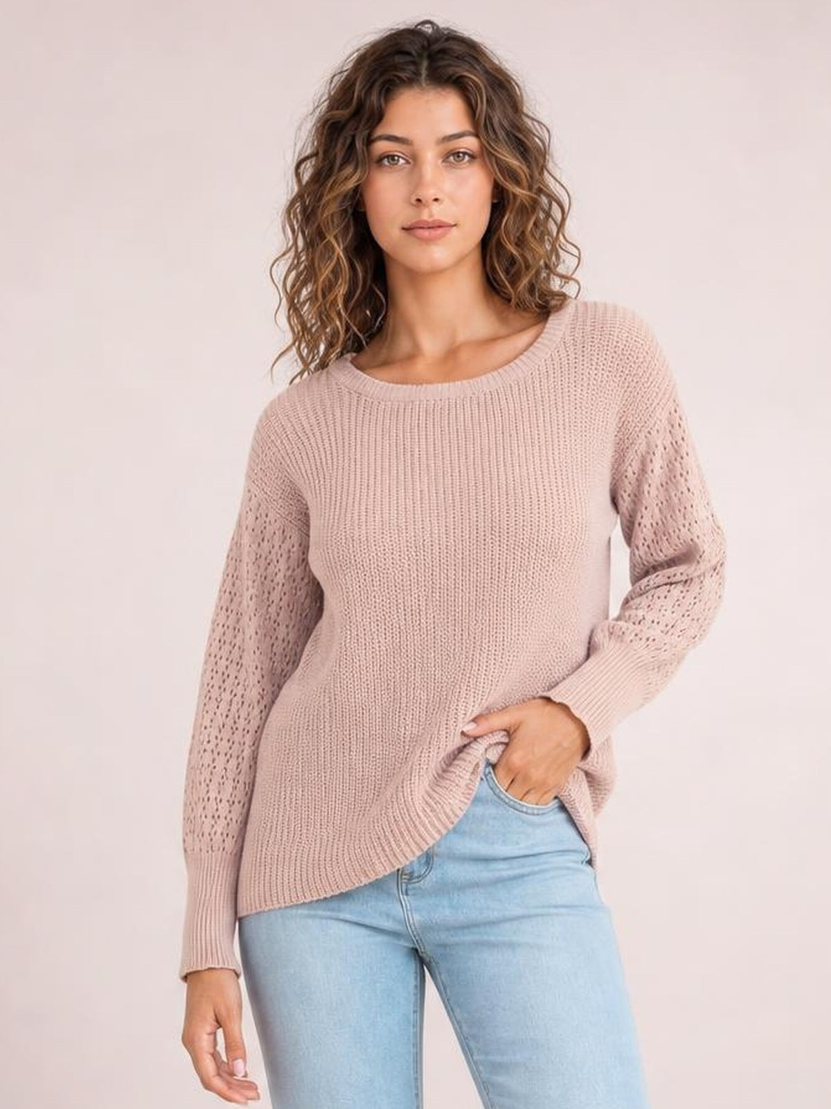 Model wearing a blush pink ribbed pullover sweater with a round neck, dropped shoulders, long openwork sleeves, ribbed cuffs, and a regular silhouette.