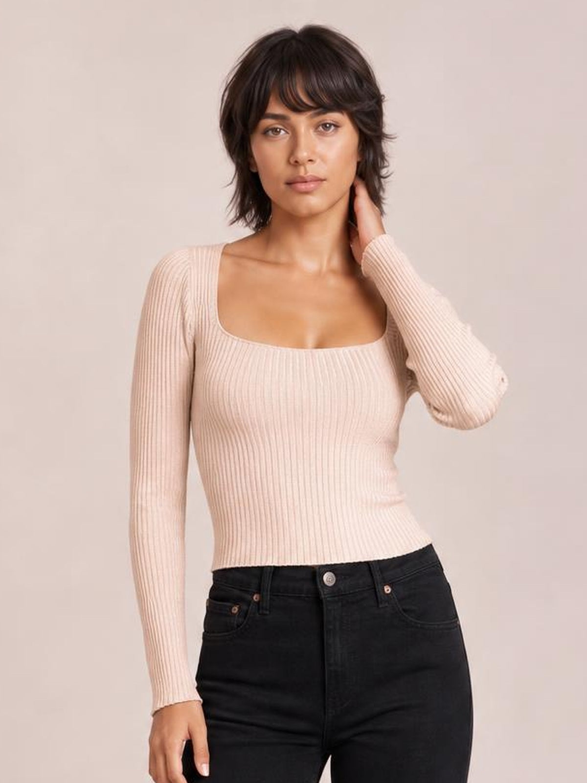 Model poses in a blush pink ribbed square neck sweater with fitted long sleeves and a stretchy, body-hugging silhouette.