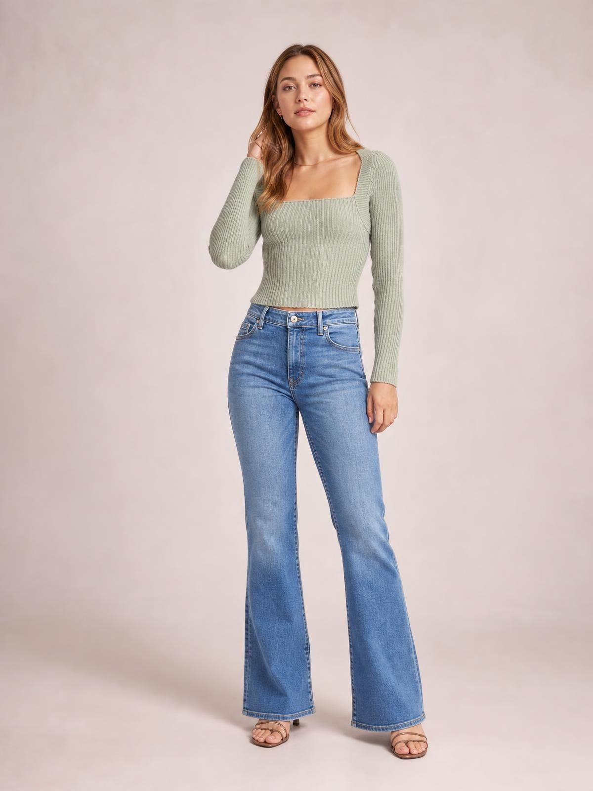 A model poses in a sage green ribbed sweater with a square neckline, long sleeves, fitted cropped silhouette, and stretchy close-knit construction.