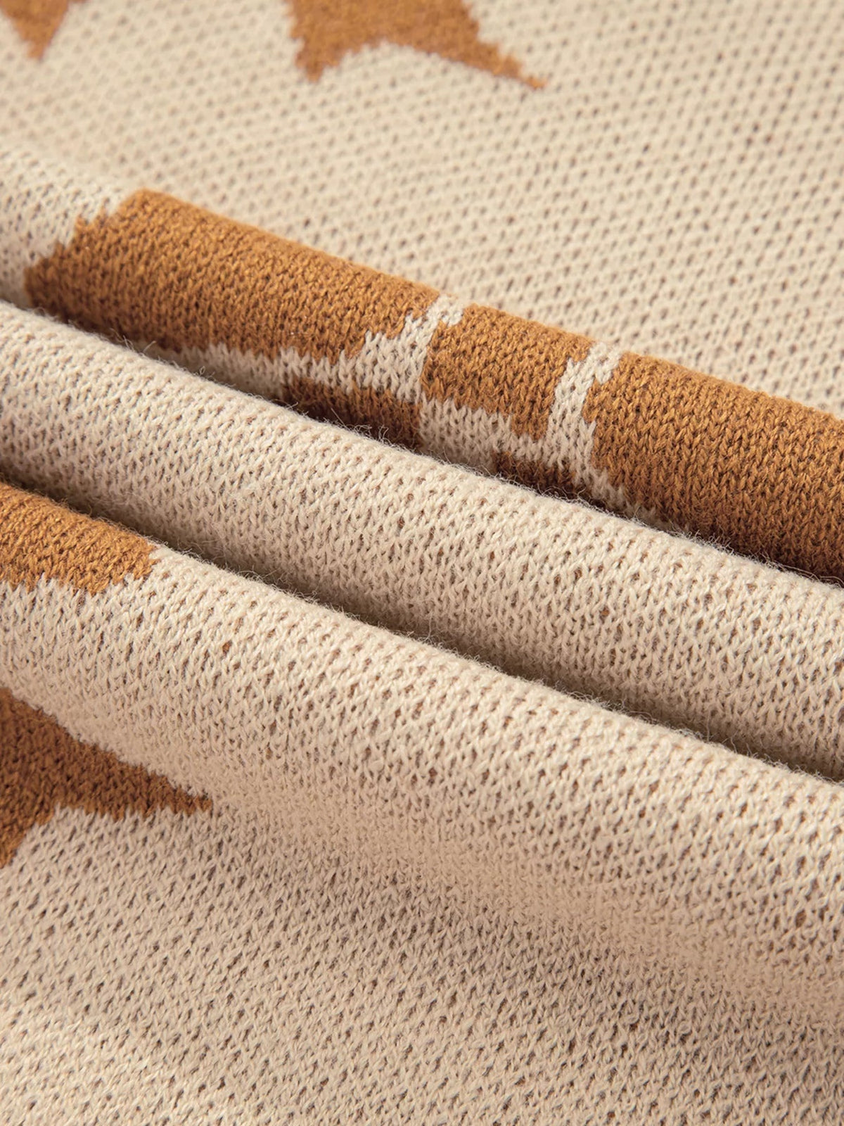 Close-up of a cream knit sweater featuring textured construction and camel-brown striped sections with a soft, slightly fuzzy finish.