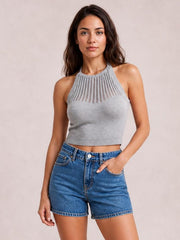 Model poses with one hand in the pocket of blue denim slouchy shorts featuring a relaxed high-waisted fit, belt loops, front pockets, and cuffed hems.