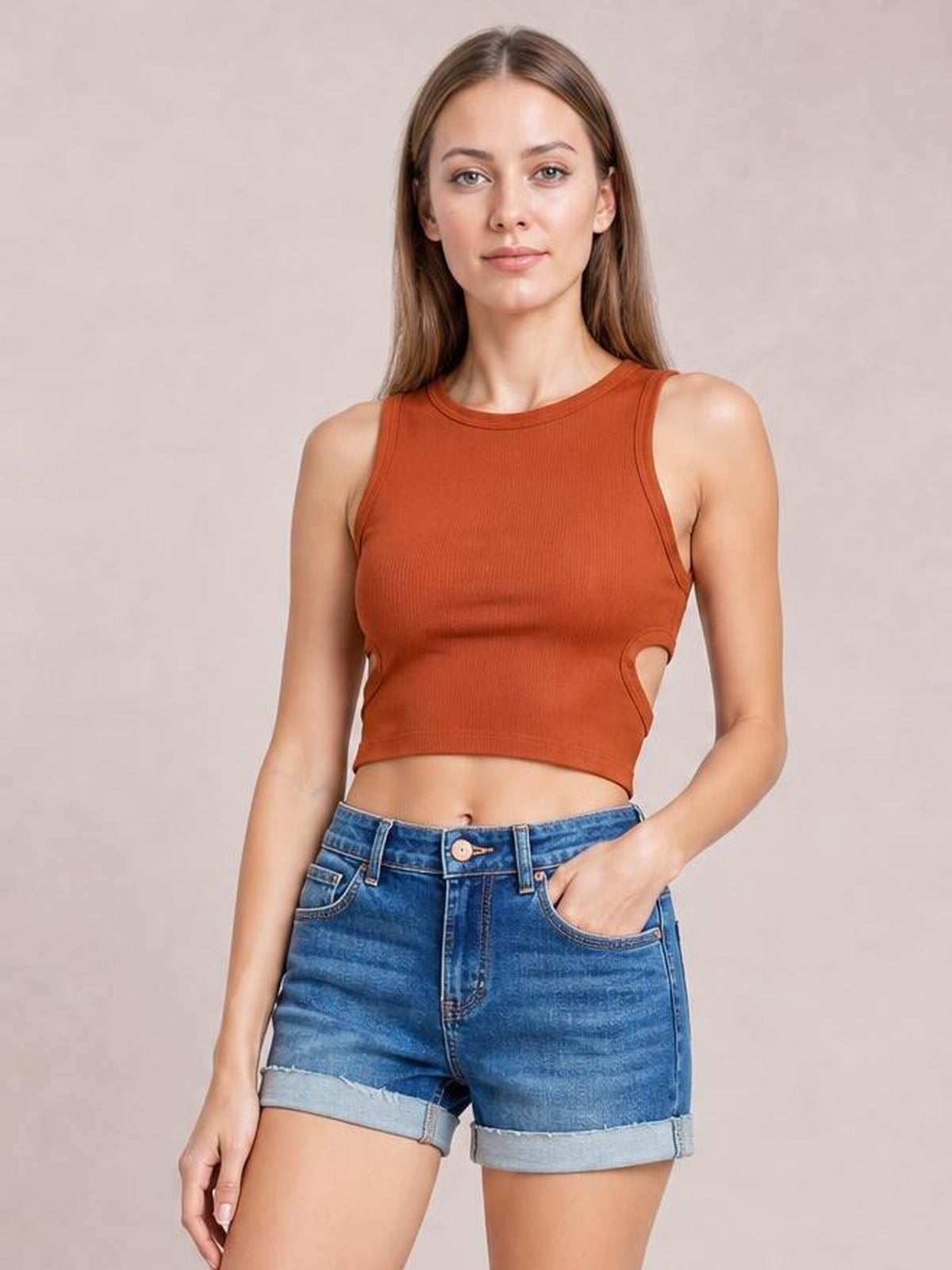 Model wearing blue low rise denim shorts with rolled cuffed hems, a relaxed fit, front button closure, and five-pocket construction.