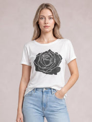 Model wears a white rose graphic round neck short sleeve T-shirt with a relaxed silhouette, shown front-facing with one hand in her jeans pocket.