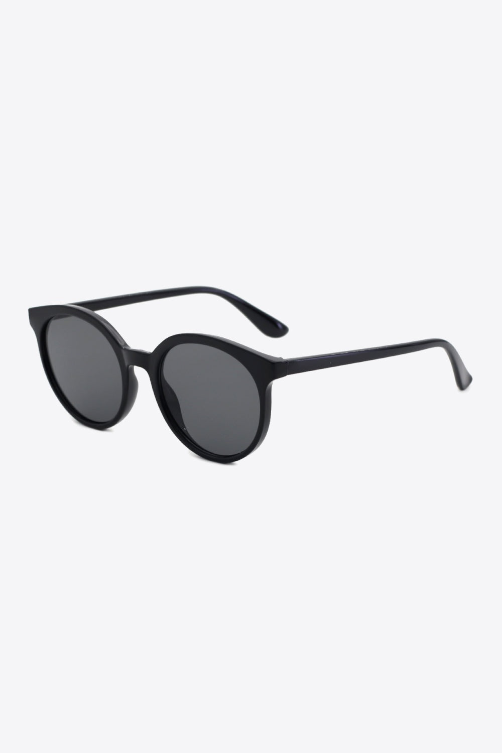 Black round full-rim sunglasses feature a softly curved polycarbonate frame, dark acetate lenses, and slim temples shown at an angled view.