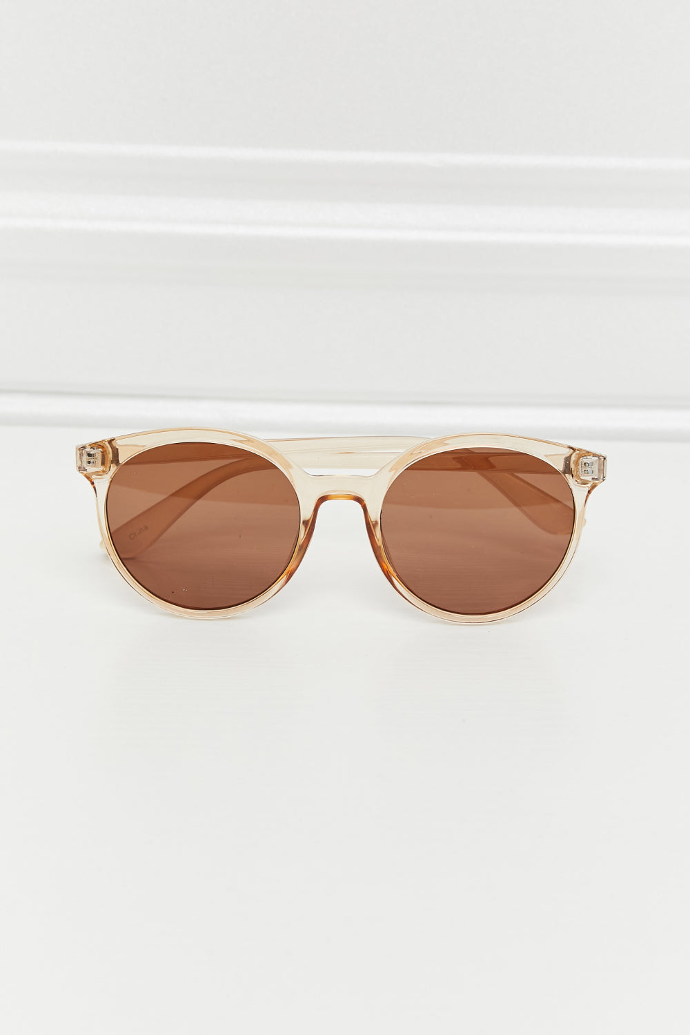 Round full-rim sunglasses feature a softly curved translucent amber polycarbonate frame with brown acetate lenses and matching structured temples.