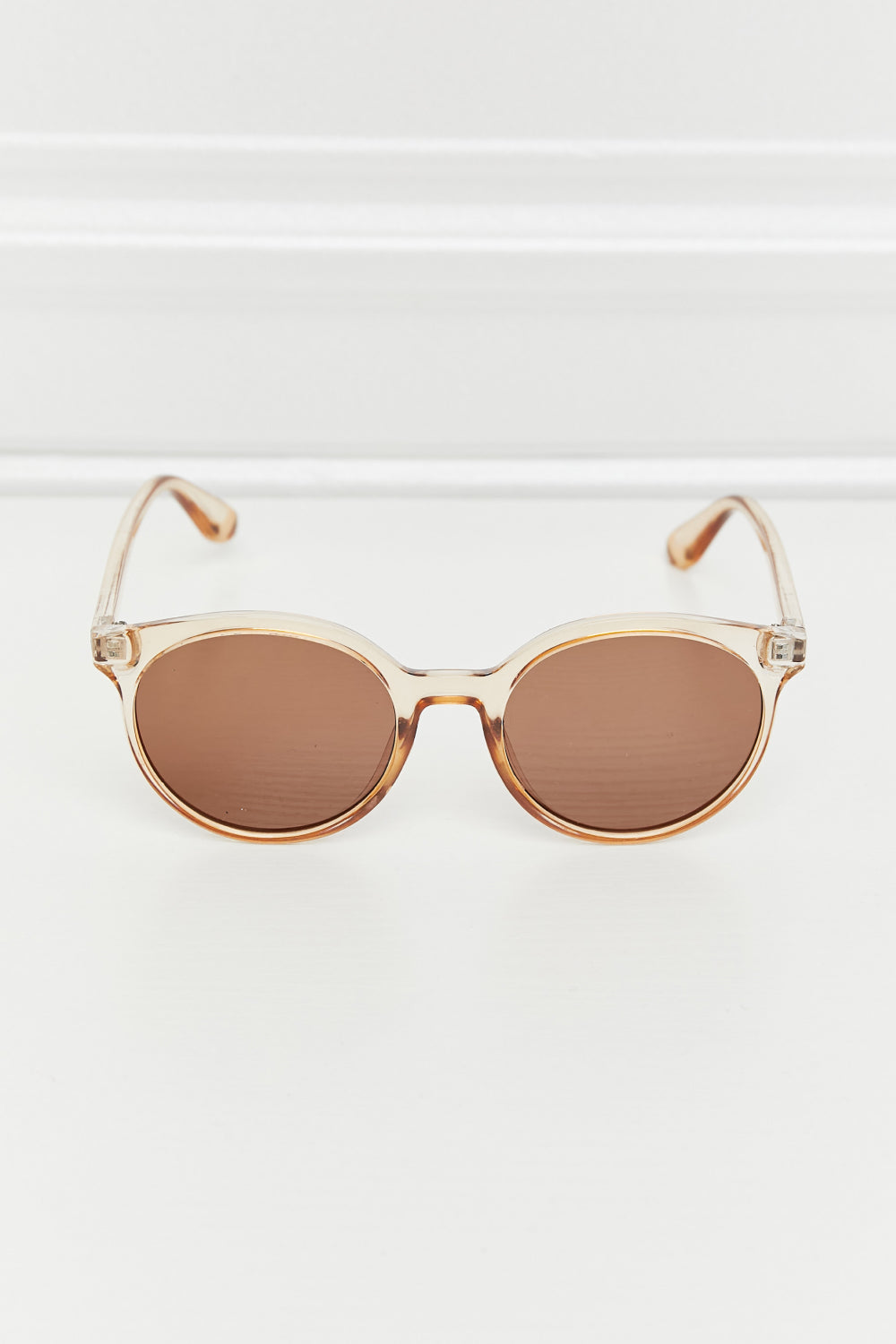 Round full-rim sunglasses feature a softly curved translucent amber polycarbonate frame, warm brown acetate lenses, a defined bridge, and slim temples.