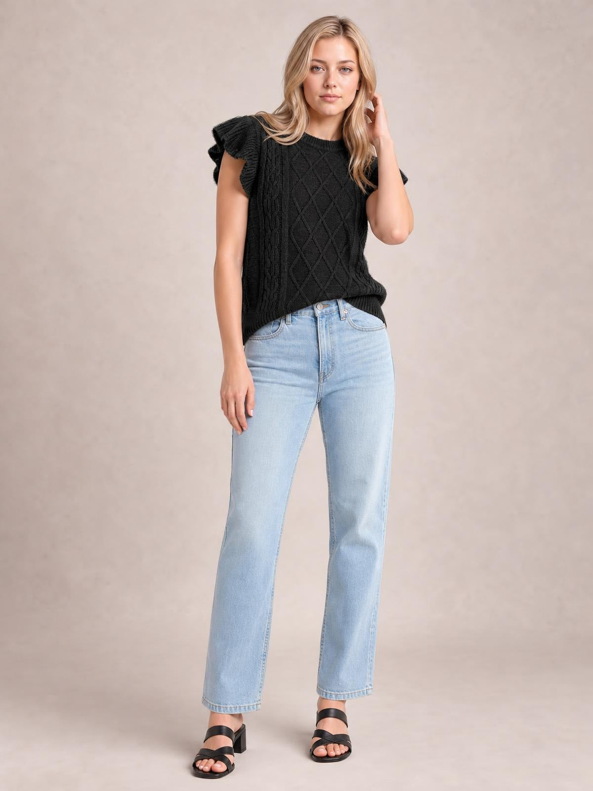 Model wears a black round-neck cap-sleeve sweater with ruffled shoulders, textured cable-knit panels, a relaxed silhouette, and ribbed hem.