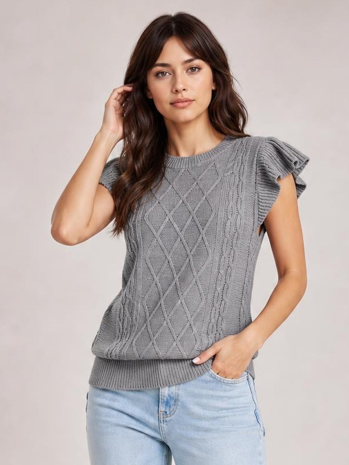 Model wearing a gray round neck cap sleeve sweater with ruffled sleeves, cable-knit diamond detailing, ribbed trim, and a relaxed silhouette.