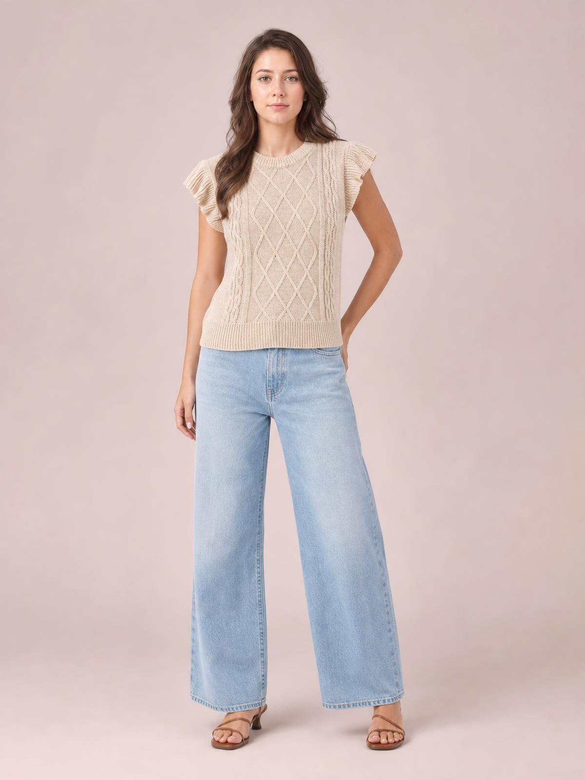 Model poses in a cream round-neck cable-knit sweater with ruffled cap sleeves, a relaxed straight silhouette, and ribbed neckline and hem.