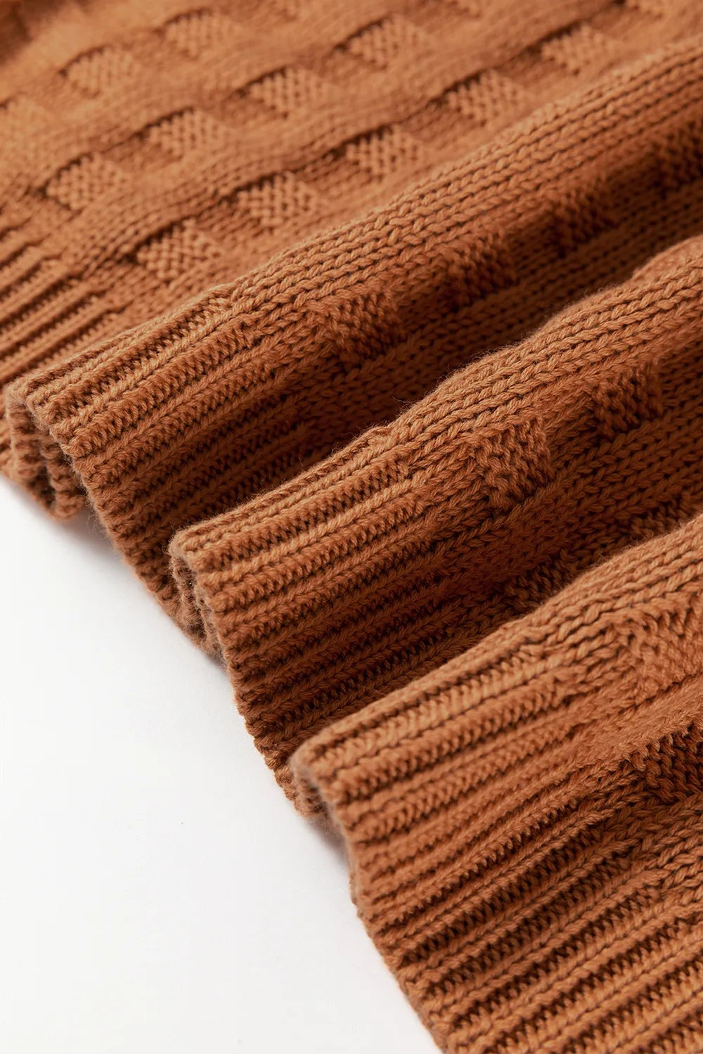 Close-up of a warm brown knitted sweater vest showing fine textured stitching, a soft slightly stretchy weave, and neatly finished ribbed edges.