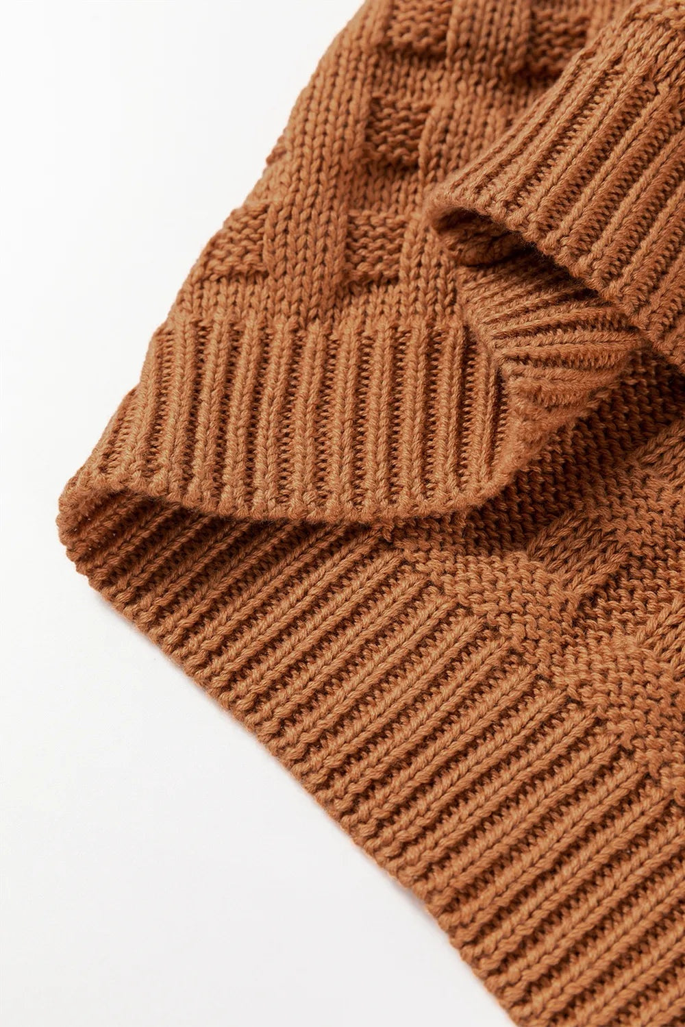 Close-up of a warm brown sweater vest featuring textured knit construction, a structured ribbed hem, and neatly finished edges.