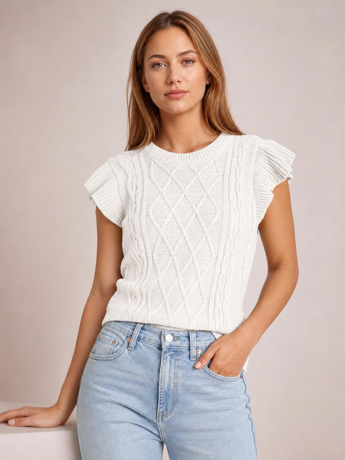 Model wearing a white round neck cap sleeve sweater with ruffled shoulders, cable-knit diamond detailing, ribbed trim, and a relaxed straight silhouette.