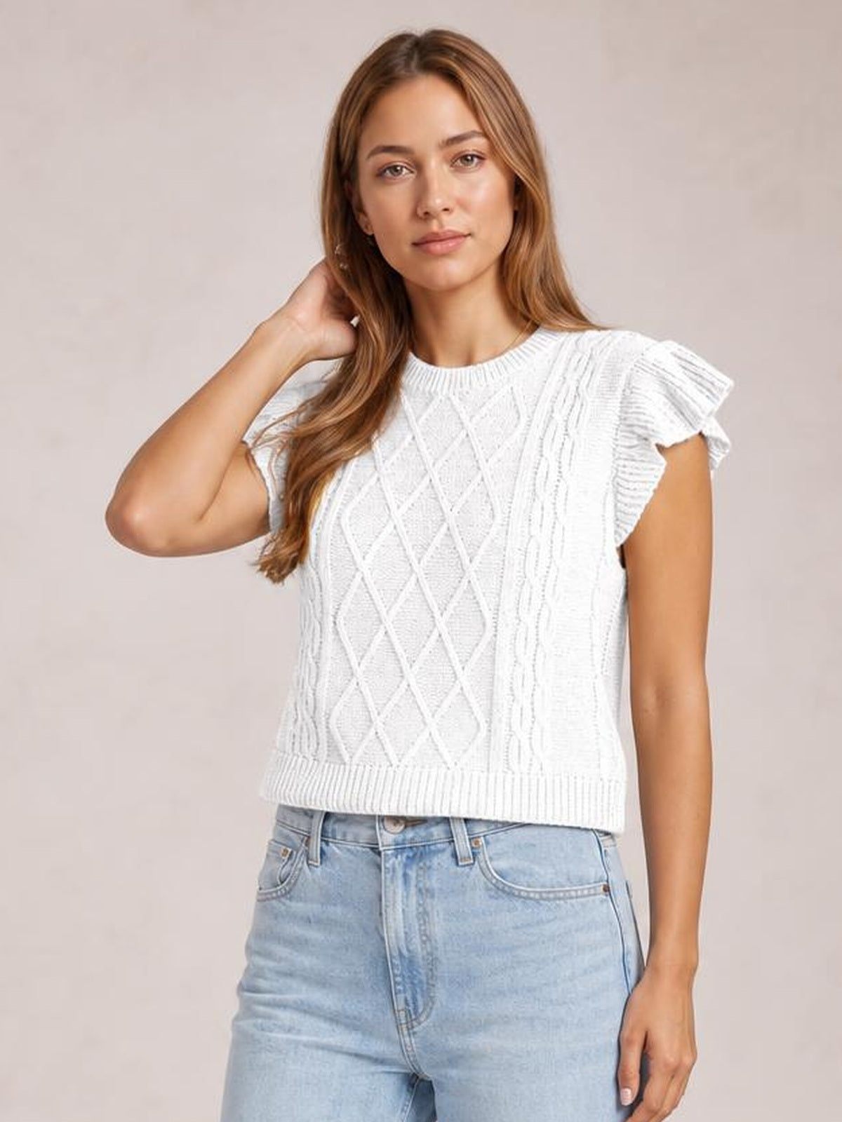 Model poses in a white round-neck cap-sleeve sweater with ruffled edges, cable-knit diamond texture, ribbed trim, and a straight silhouette.
