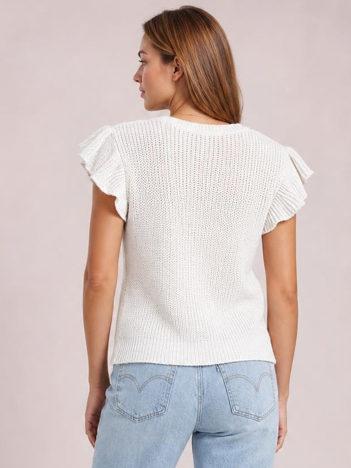 Model shown from behind wearing a white round-neck cable-knit sweater with ruffled cap sleeves, straight silhouette, and ribbed hem.