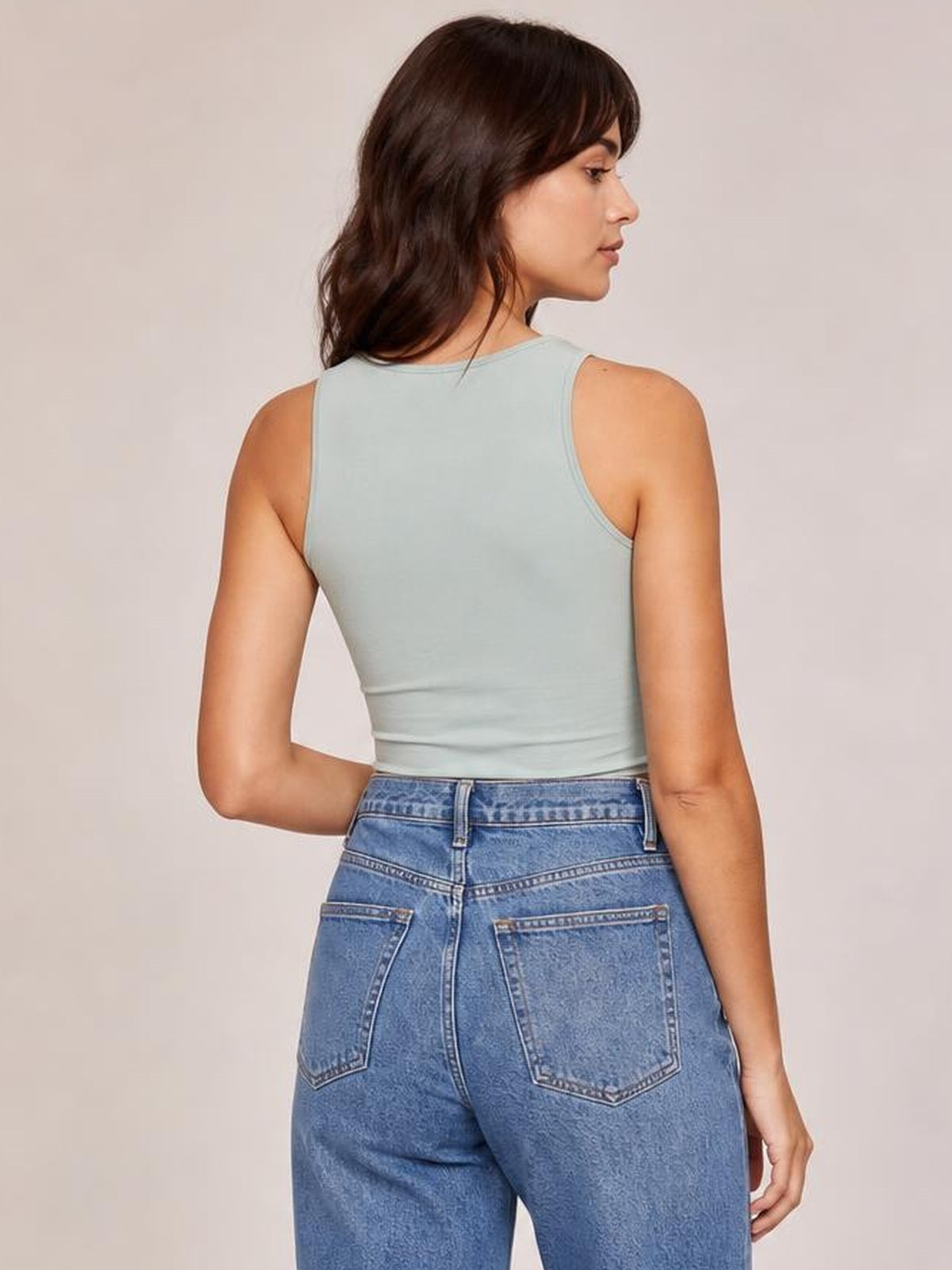 Model shown from behind wears a pale blue round-neck cropped tank with a fitted stretchy silhouette, sleeveless cut, and neatly bound neckline and armholes.