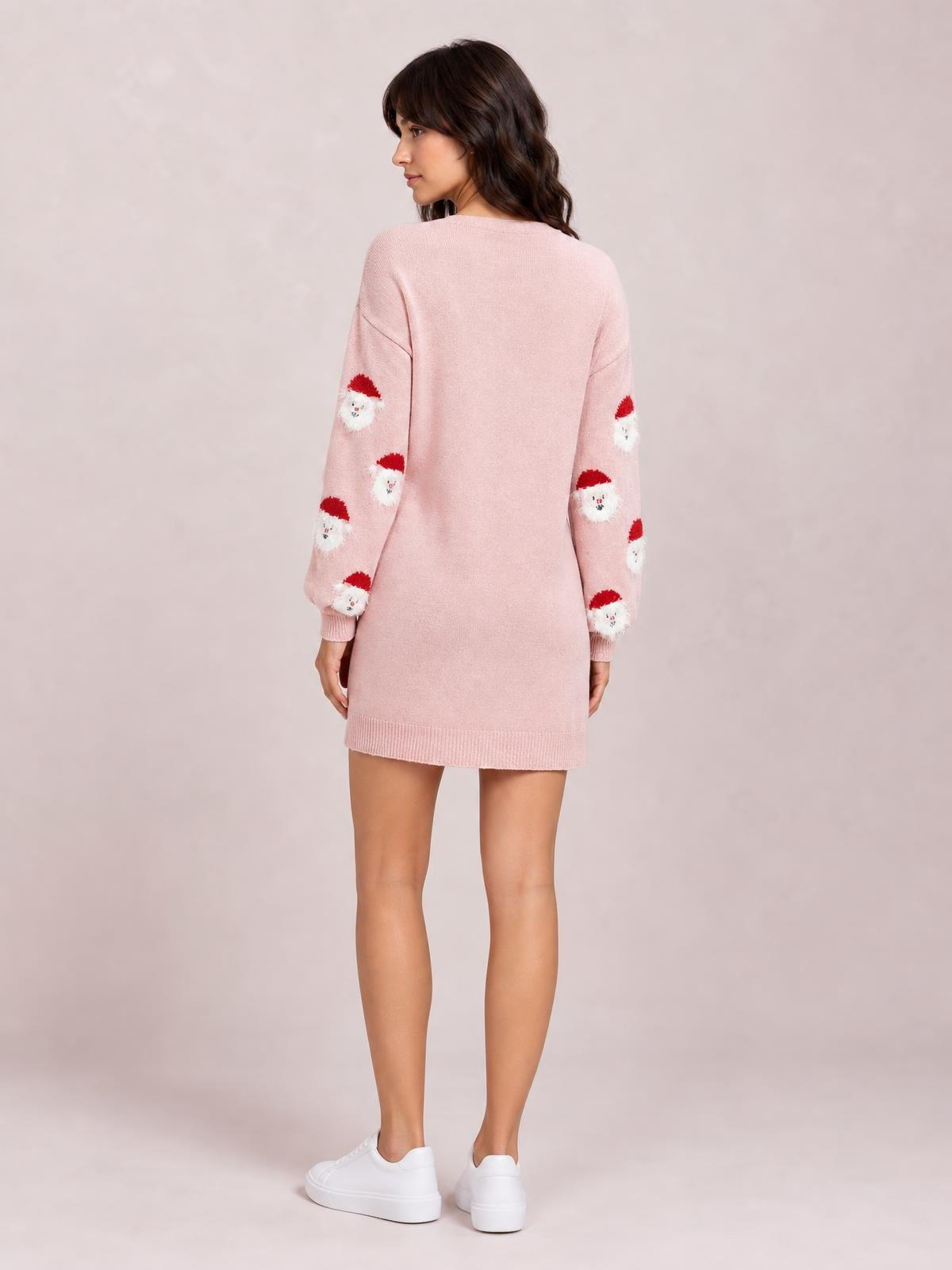 A model poses in a pink round-neck sweater dress with dropped shoulders, long sleeves featuring Santa motifs, ribbed cuffs and hem, and a straight mini silhouette.
