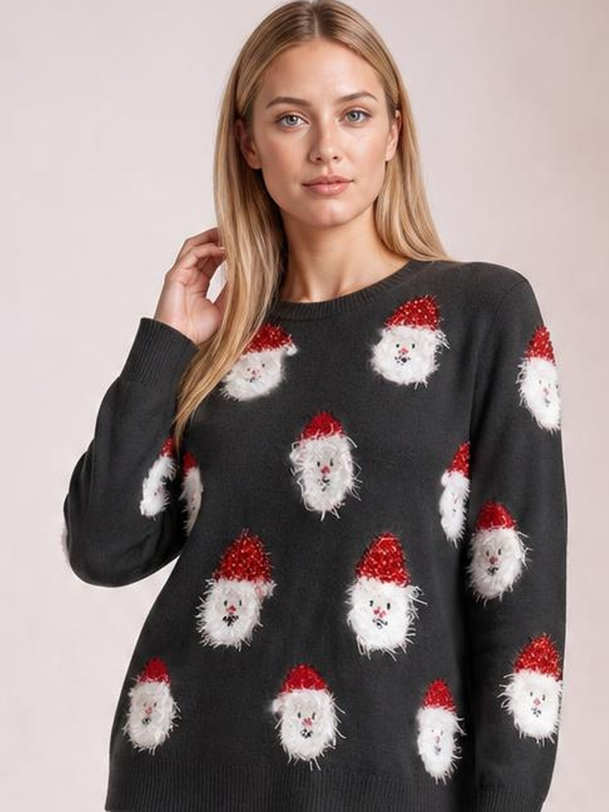 A model poses with one hand in her hair wearing a black round-neck dropped-shoulder sweater dress with long sleeves, a relaxed fit, and Santa face motifs.