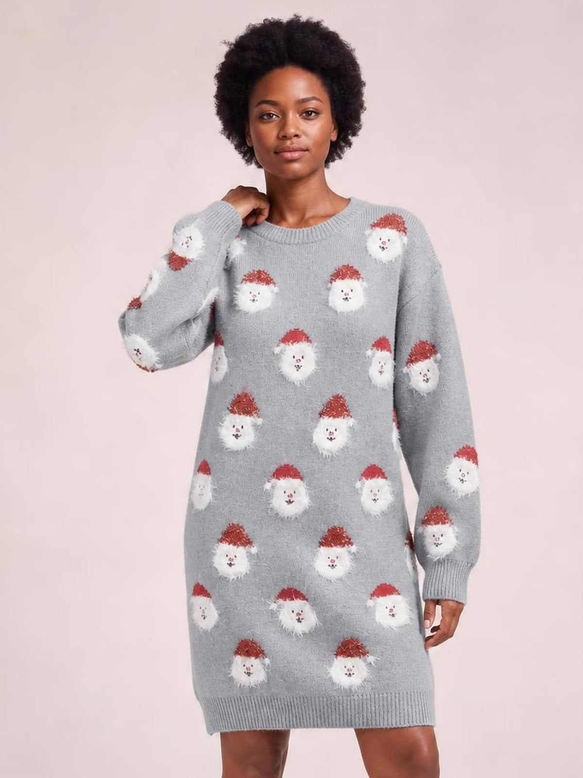 Model poses in a gray round neck dropped shoulder sweater dress with long sleeves, ribbed trim, straight relaxed silhouette, and repeating Santa face knit pattern.