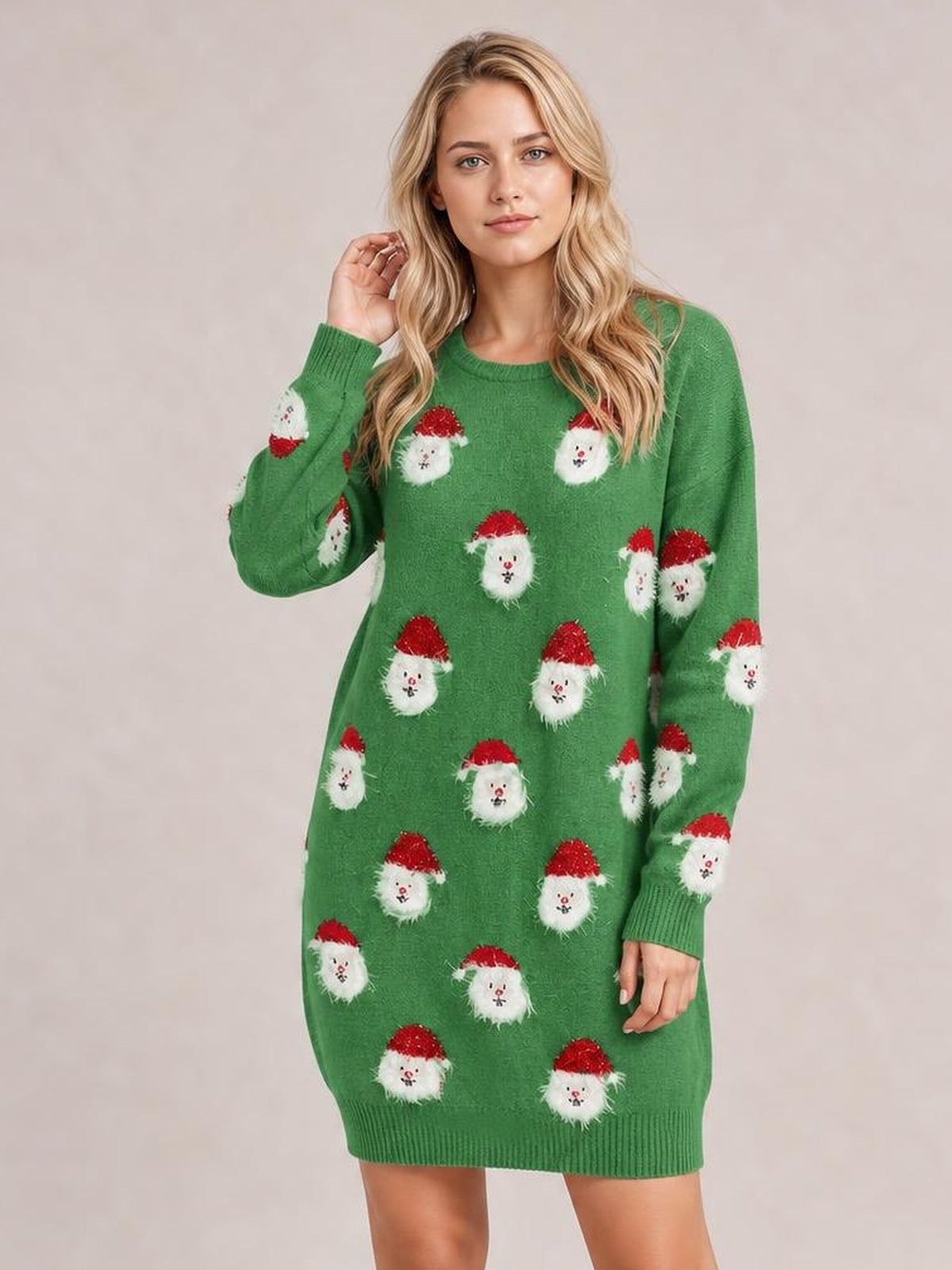 A model poses in a green round-neck sweater dress with dropped shoulders, long sleeves, ribbed cuffs and hem, a relaxed straight silhouette, and Santa face motifs.