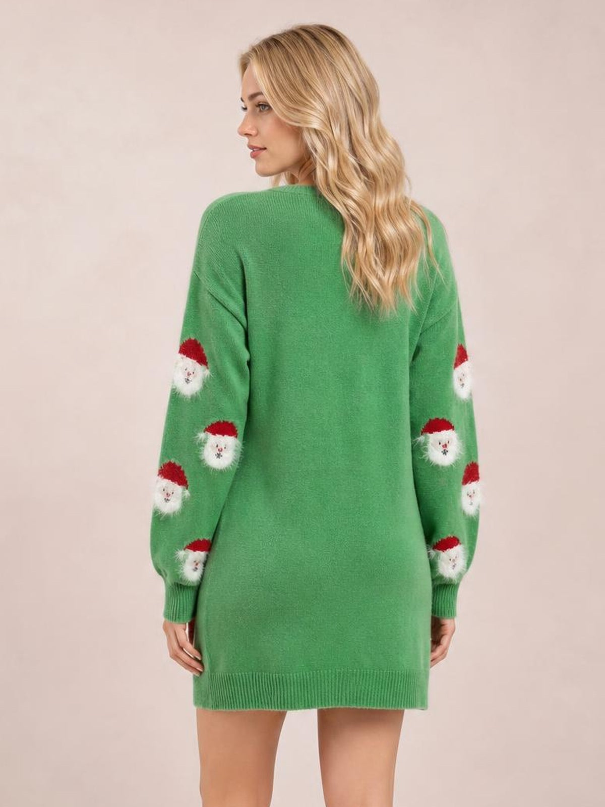A model looks over her shoulder in a green round-neck dropped-shoulder sweater dress with a relaxed silhouette, ribbed hem and Santa-print sleeves.