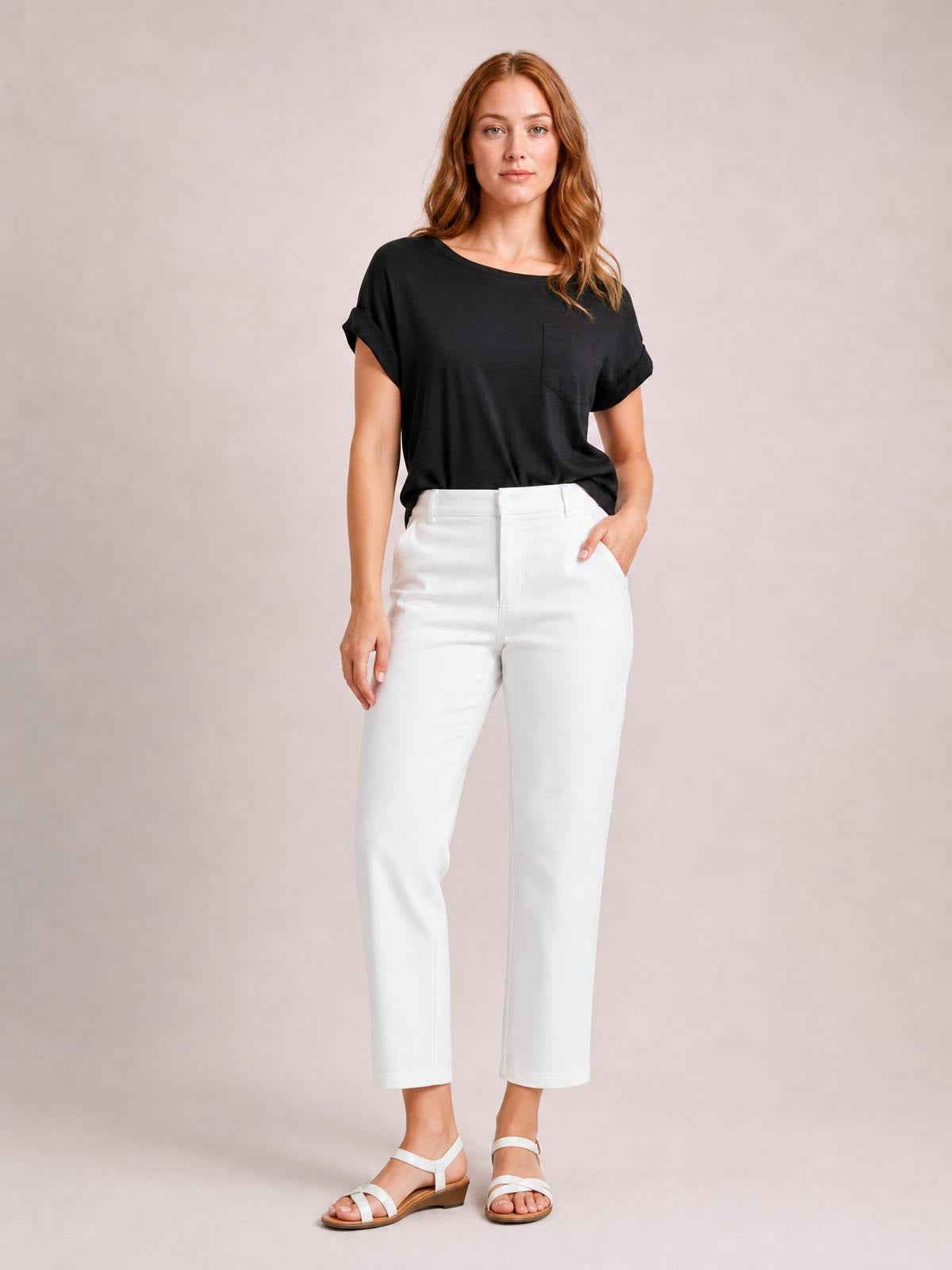 A model wears a black round neck half sleeve T-shirt with rolled cuffs, a chest pocket, and a relaxed silhouette, posing with one hand in her pocket.