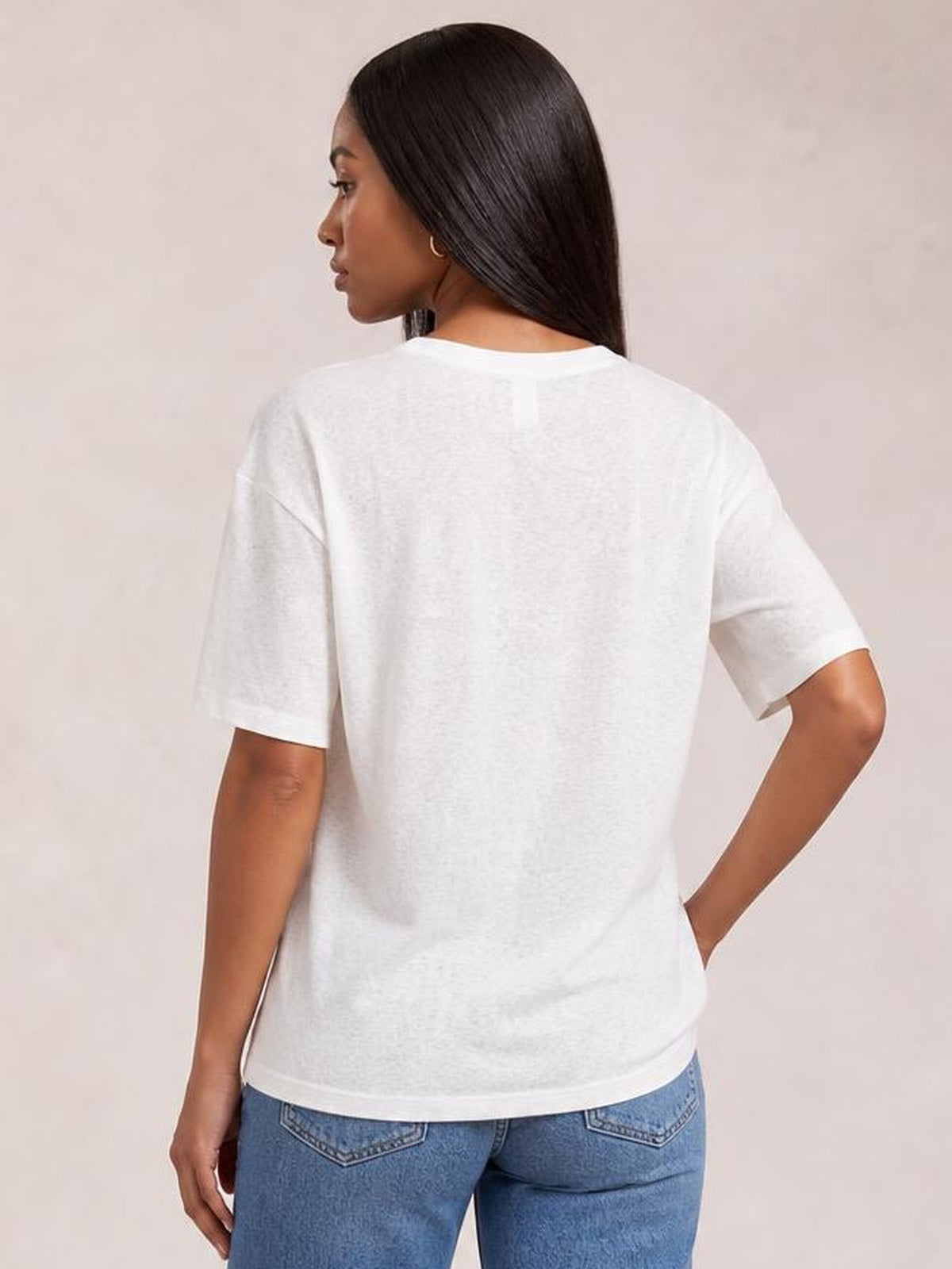 A model poses from the back in a white round neck half sleeve T-shirt with a relaxed straight silhouette and smooth opaque construction.