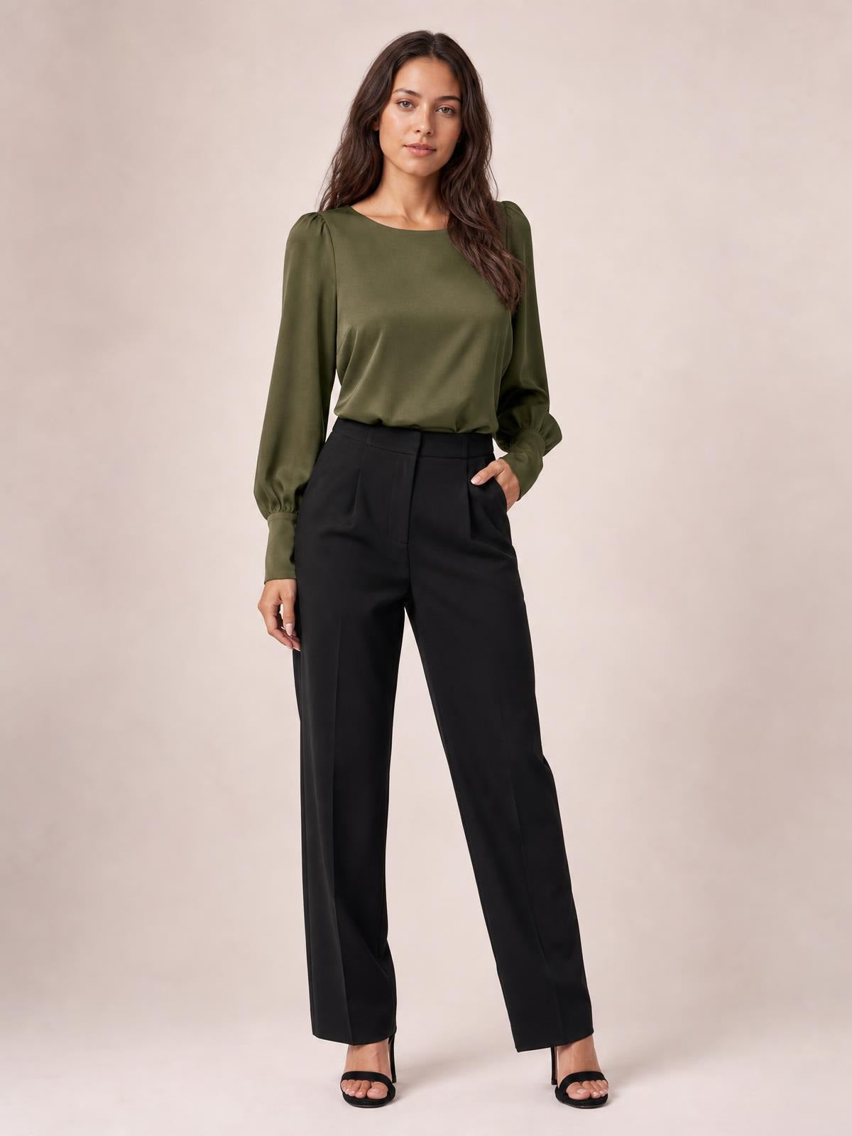 Model poses in an olive green round neck blouse with voluminous lantern sleeves, gathered cuffs, and a relaxed silhouette tucked into black trousers.