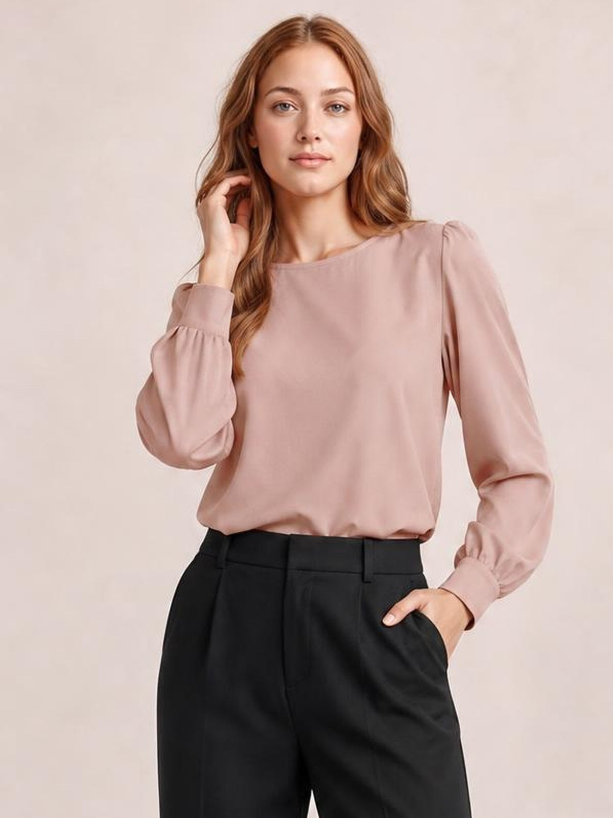 Model wearing a dusty pink round neck blouse with gathered lantern sleeves, buttoned cuffs, and a relaxed silhouette tucked into black trousers.