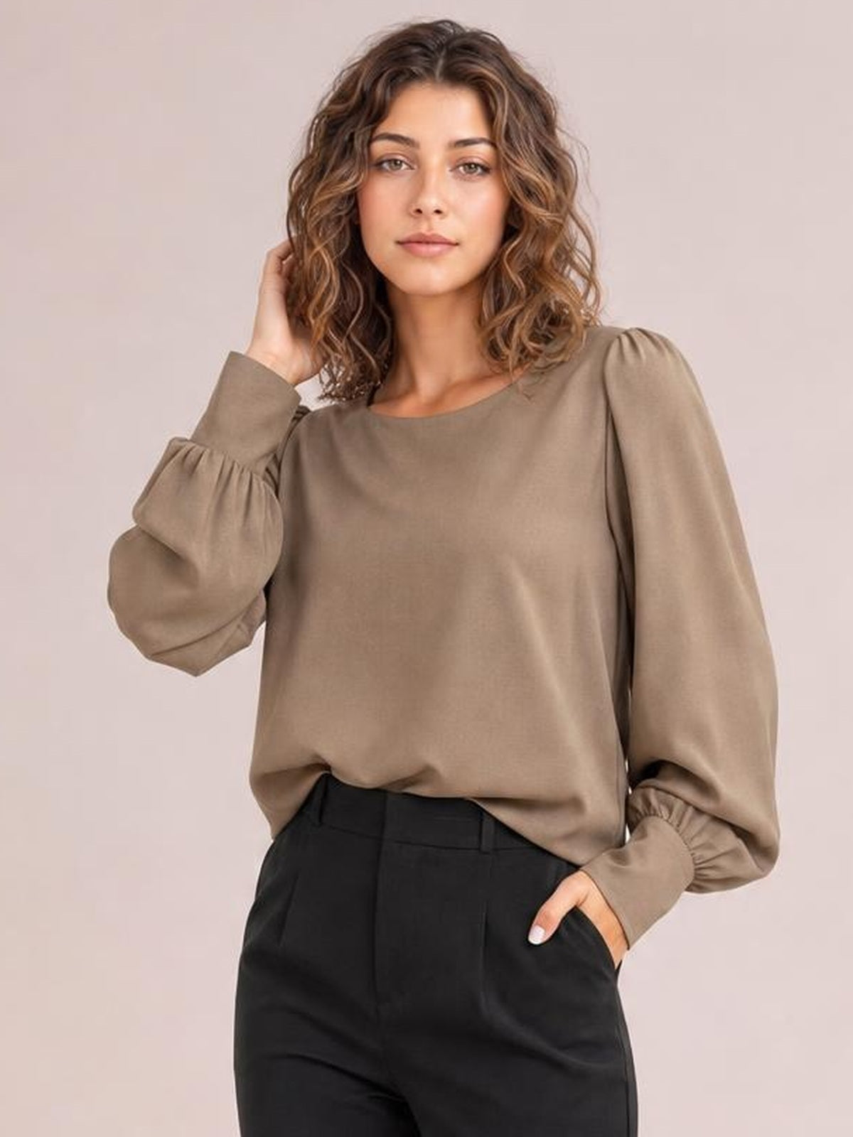 Model poses in a taupe round neck blouse with voluminous lantern sleeves, gathered cuffs, and a relaxed straight silhouette.