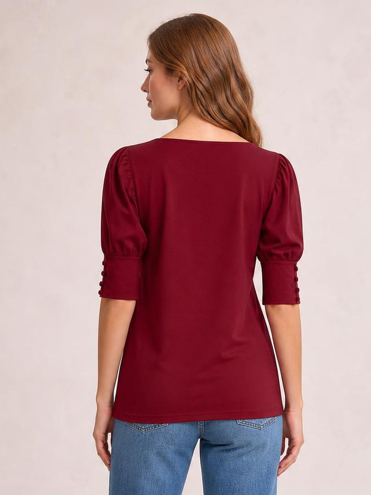 Model shown from behind wears a burgundy round neck lantern sleeve blouse with puffed sleeves, buttoned cuffs, and a relaxed straight silhouette.
