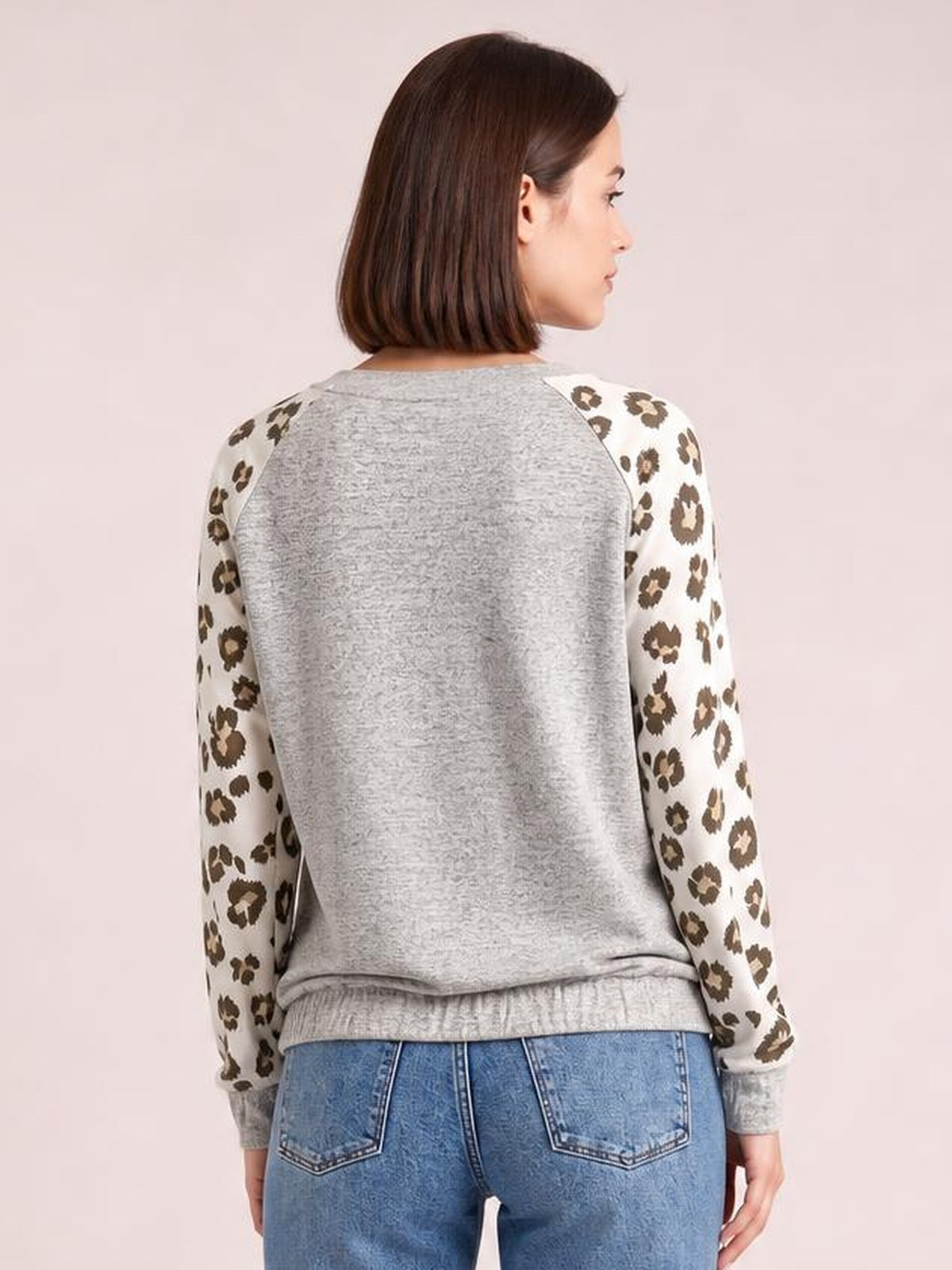 Model shown from the back wearing a heather gray round neck leopard print raglan sleeve top with a relaxed silhouette and ribbed cuffs and hem.