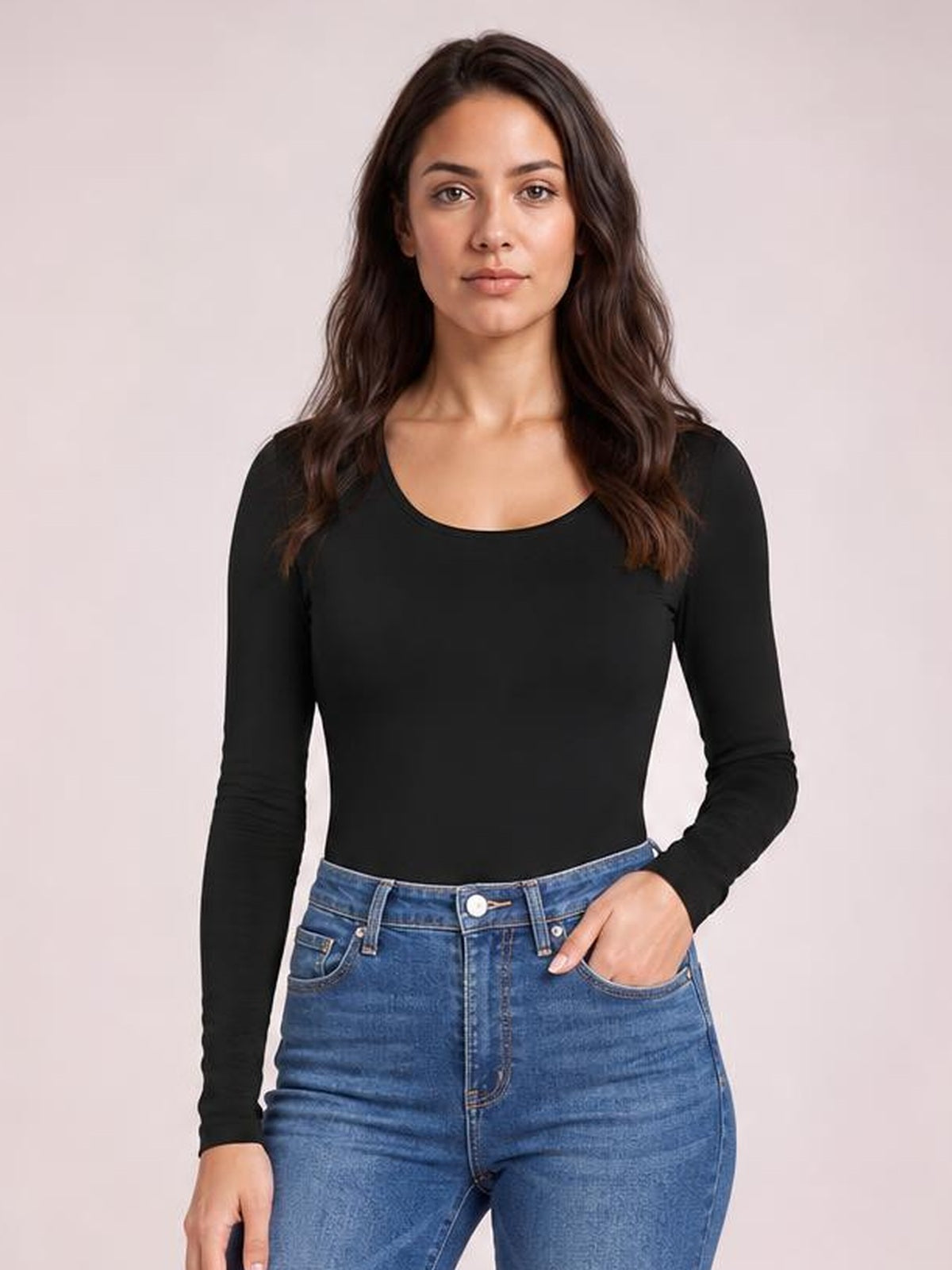 Model wears a fitted black round neck long sleeve bodysuit with an opaque, smooth silhouette, standing with one hand tucked into her jeans pocket.
