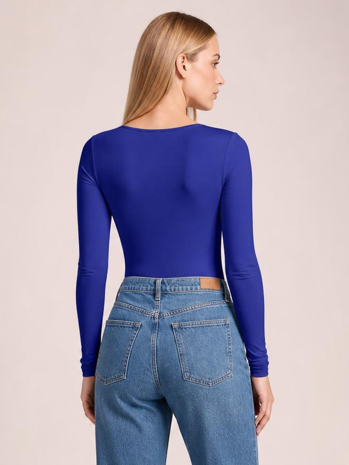 A model shown from the back wears a cobalt blue round neck long sleeve bodysuit with a smooth, fitted silhouette and moderate stretch.