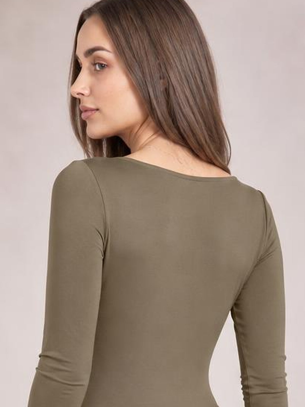 Model turned slightly to the side wears an opaque olive-brown round neck long sleeve bodysuit with a smooth, fitted silhouette and moderate stretch.