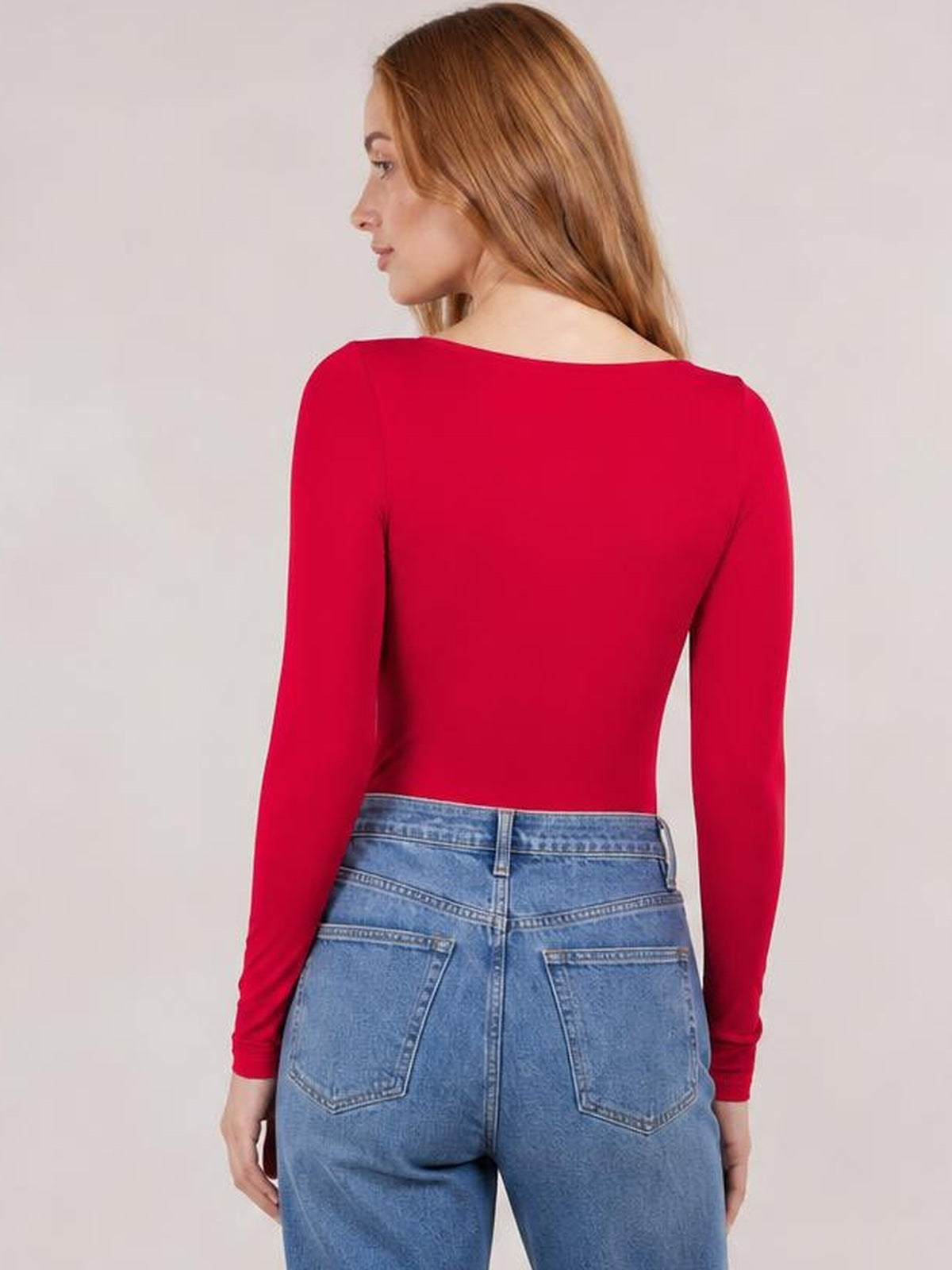 Model viewed from behind wearing a red round neck long sleeve bodysuit with a smooth, fitted silhouette and moderate stretch.