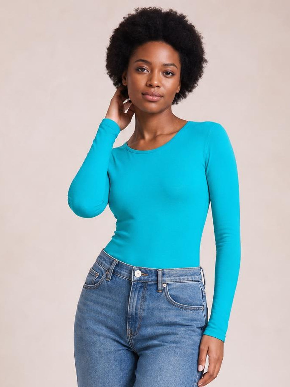Model poses in a turquoise round neck long sleeve bodysuit with a fitted silhouette, smooth opaque construction, and moderate stretch.