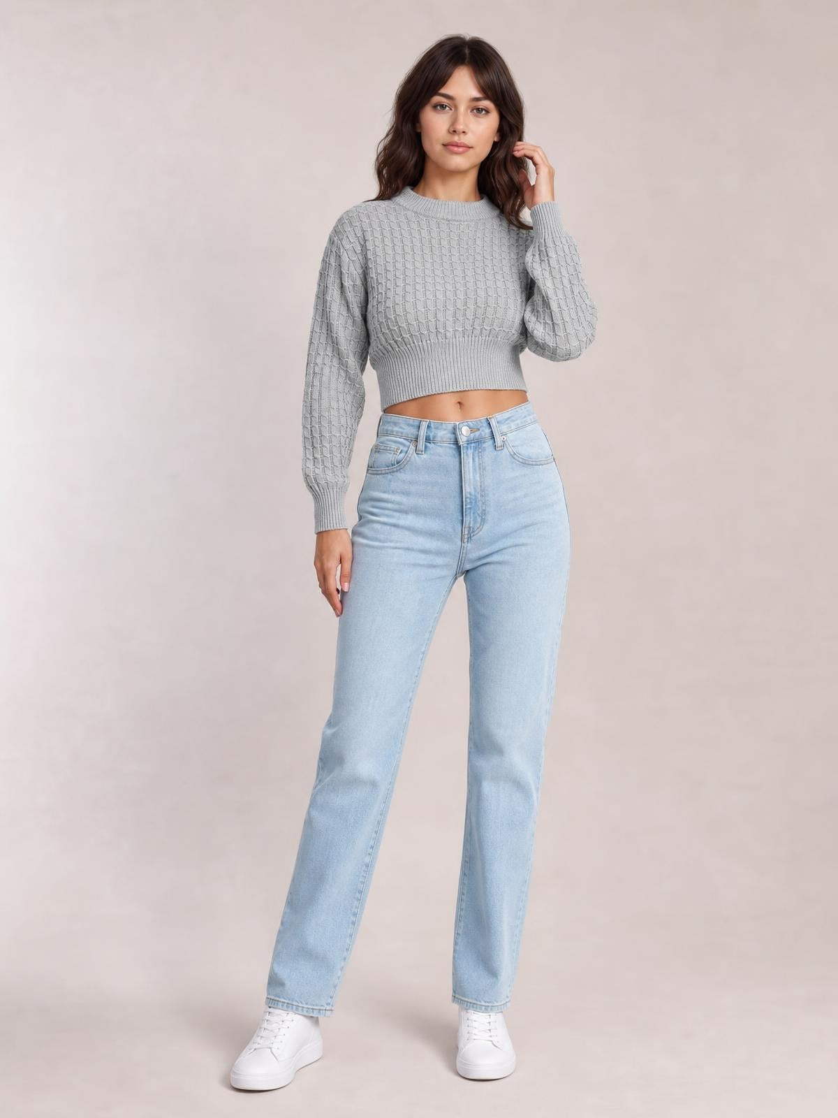 Model poses in a gray round-neck long-sleeve cropped sweater with a textured knit pattern, ribbed cuffs and hem, and a fitted cropped silhouette.