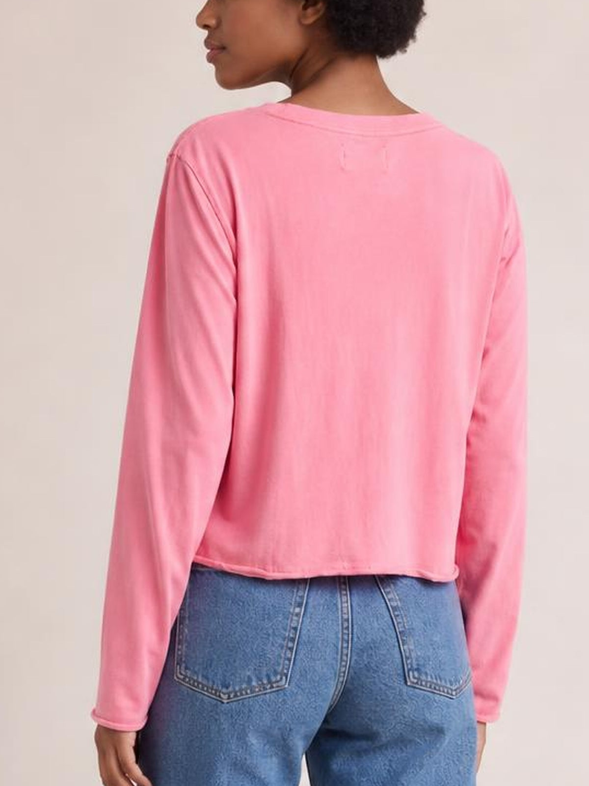 A model shown from behind wears a pink round-neck long-sleeve cropped T-shirt with a relaxed, straight silhouette and clean hem.