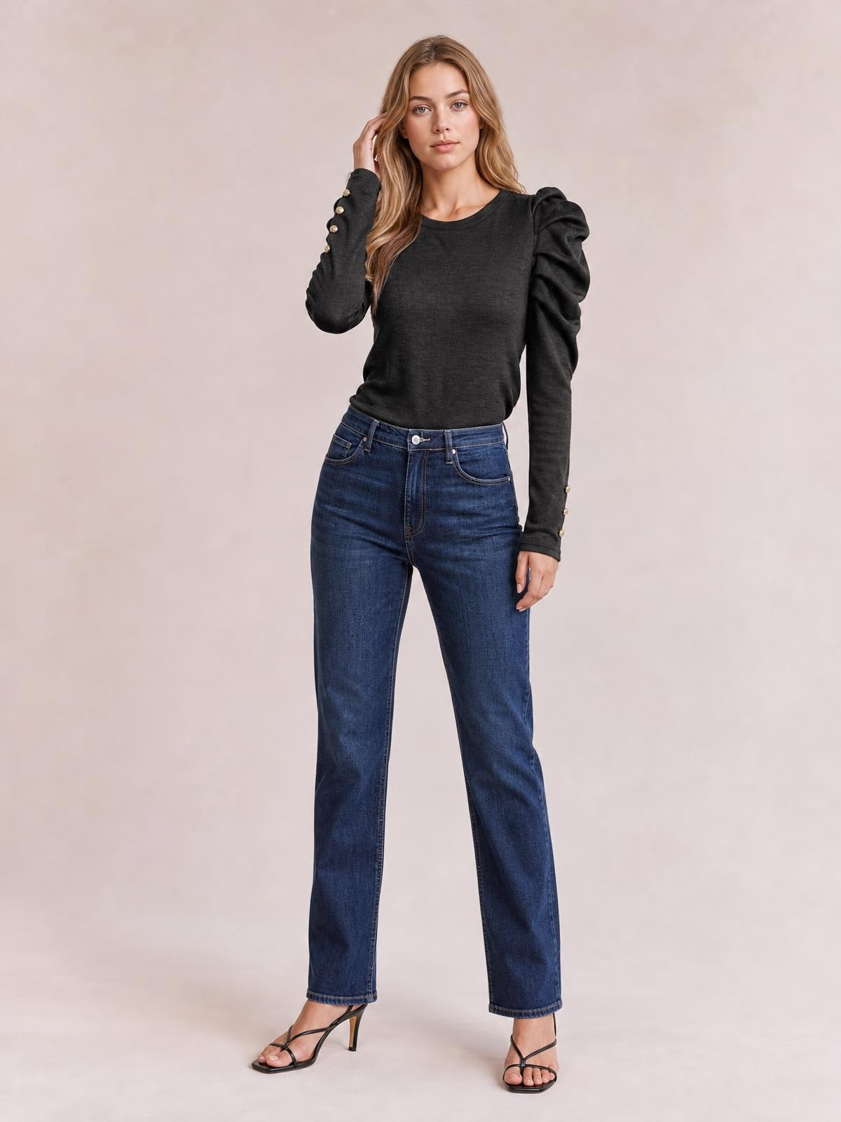 Model in a black round-neck blouse with dramatic puff sleeves, ruched shoulder construction, buttoned cuffs, and a relaxed silhouette, paired with straight-leg jeans.