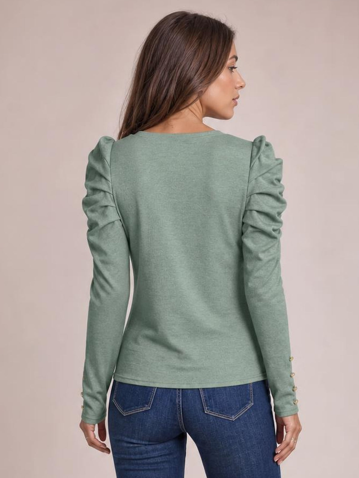 Model shown from the back wears a sage green round-neck blouse with puffed, ruched long sleeves, a straight silhouette, and buttoned cuffs.