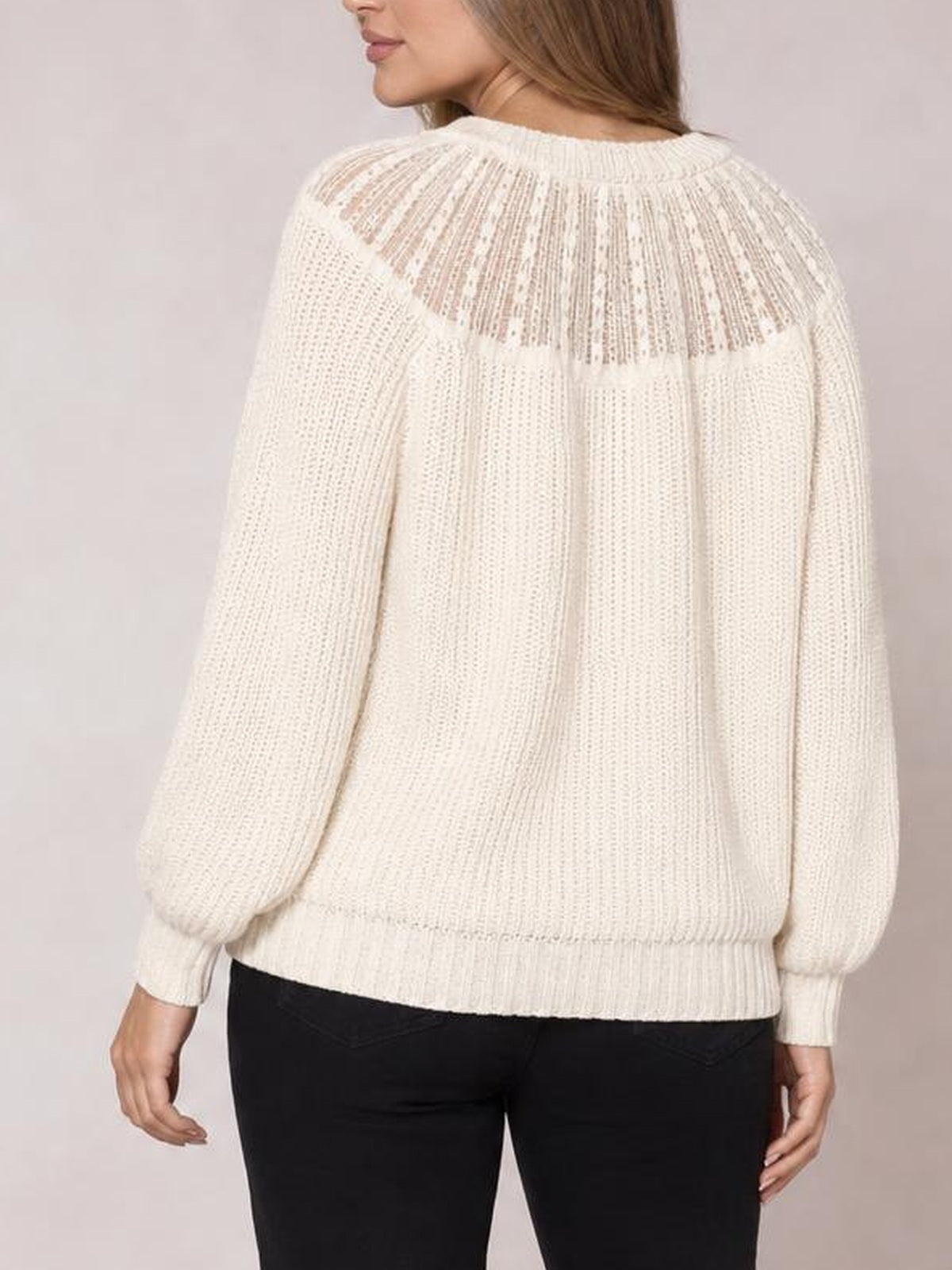 A model shows the back of a cream round-neck rib-knit sweater with long sleeves, a relaxed silhouette, semi-sheer open knit, and ribbed cuffs and hem.
