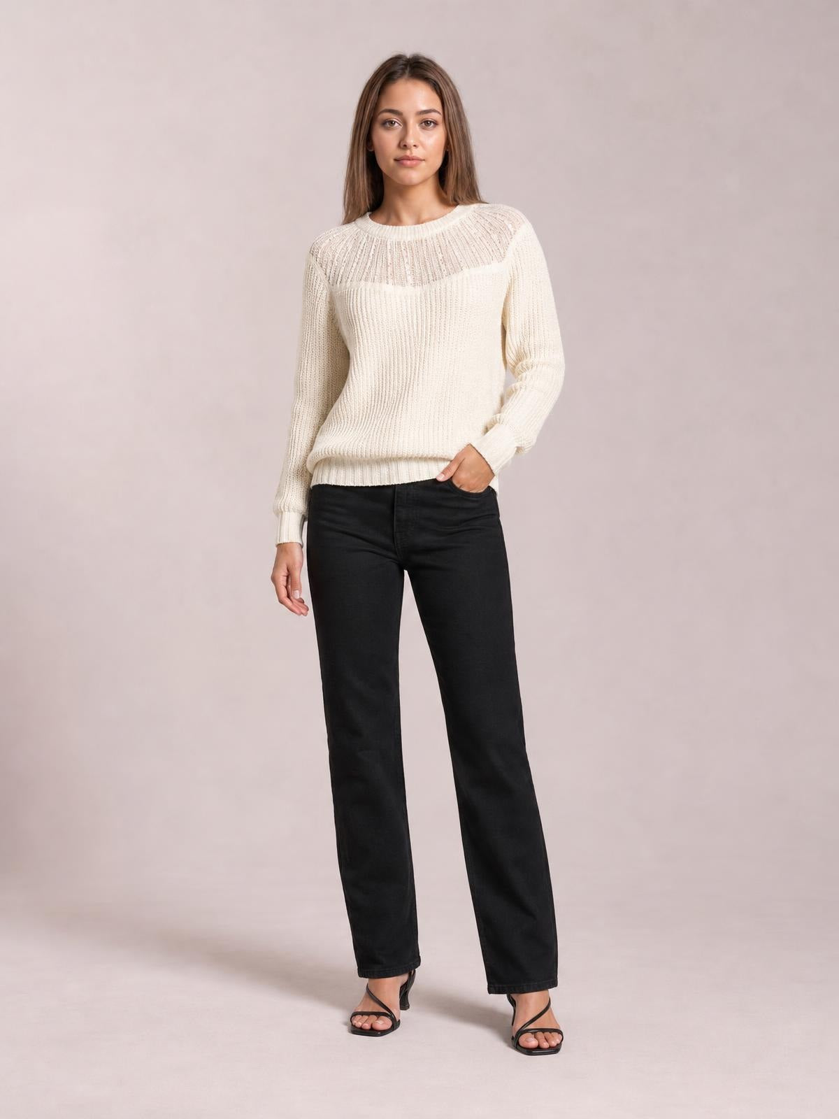 Model poses in a cream round neck rib-knit sweater with long sleeves, a semi-sheer yoke, vertical texture, and a relaxed straight silhouette.