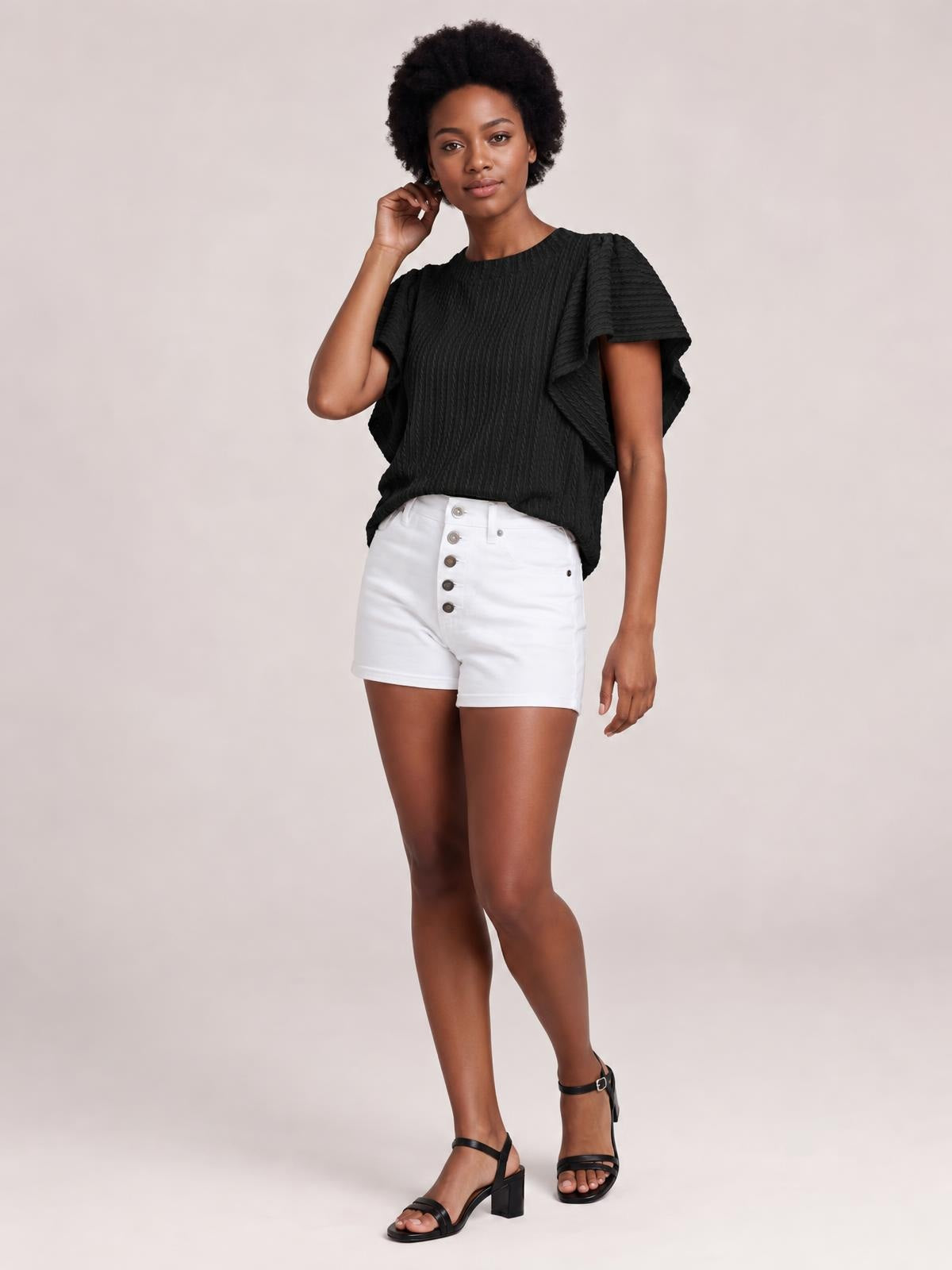 Model poses in a black round neck top with layered ruffle sleeves, a textured construction, and a relaxed, slightly cropped silhouette.