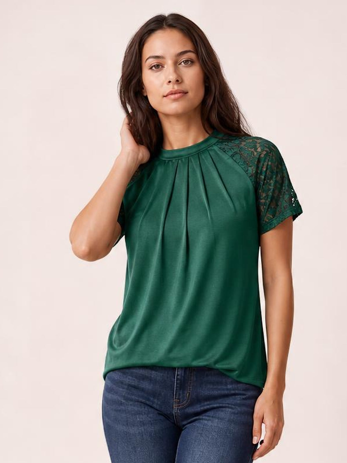 A model poses in a forest green round neck short sleeve T-shirt with lace sleeve details, a pleated front, and a relaxed straight silhouette.