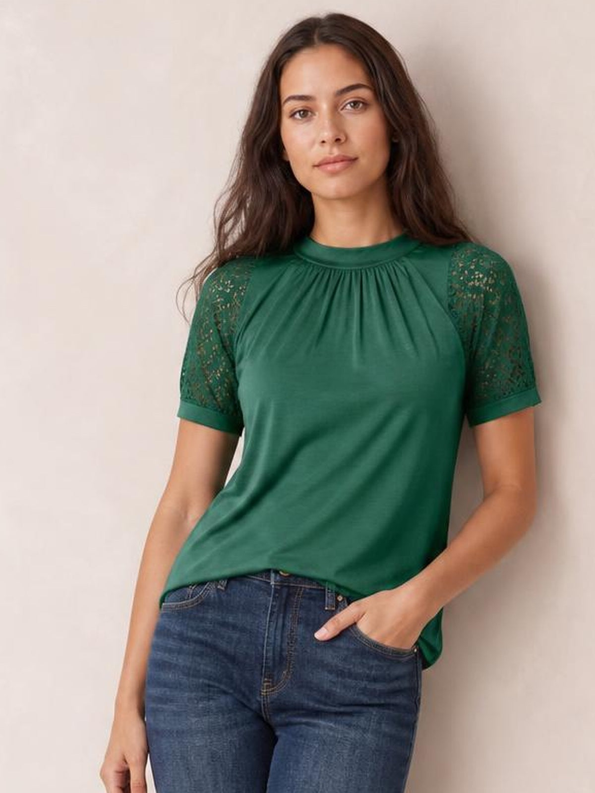 Model poses in a green round neck short sleeve T-shirt with a relaxed silhouette, gathered neckline, and lace detail on the sleeves.