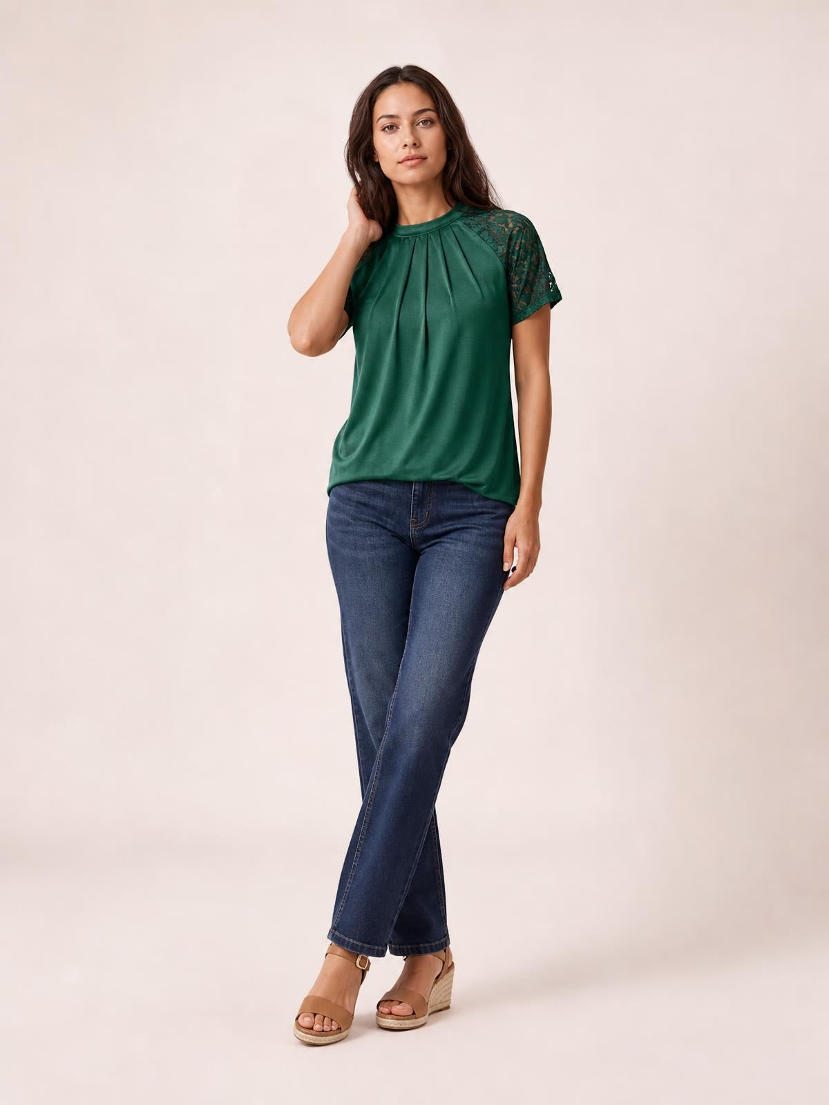 Model poses in a forest-green round neck short sleeve T-shirt with pleated detailing and lace sleeves, styled in a relaxed silhouette with jeans.